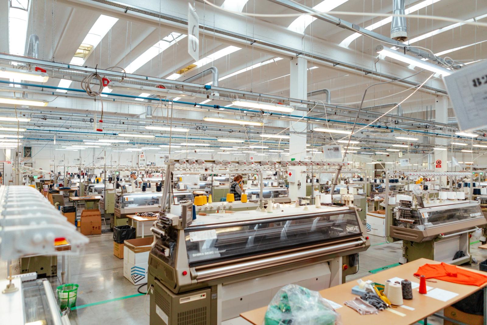 Rows of industrial knitting machines on a bright factory floor