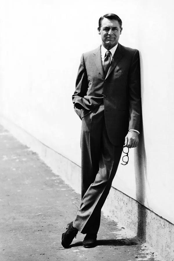 Cary Grant in a suit leaning against a white wall