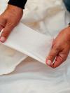 Hands inspecting a panel of white knitted fabric