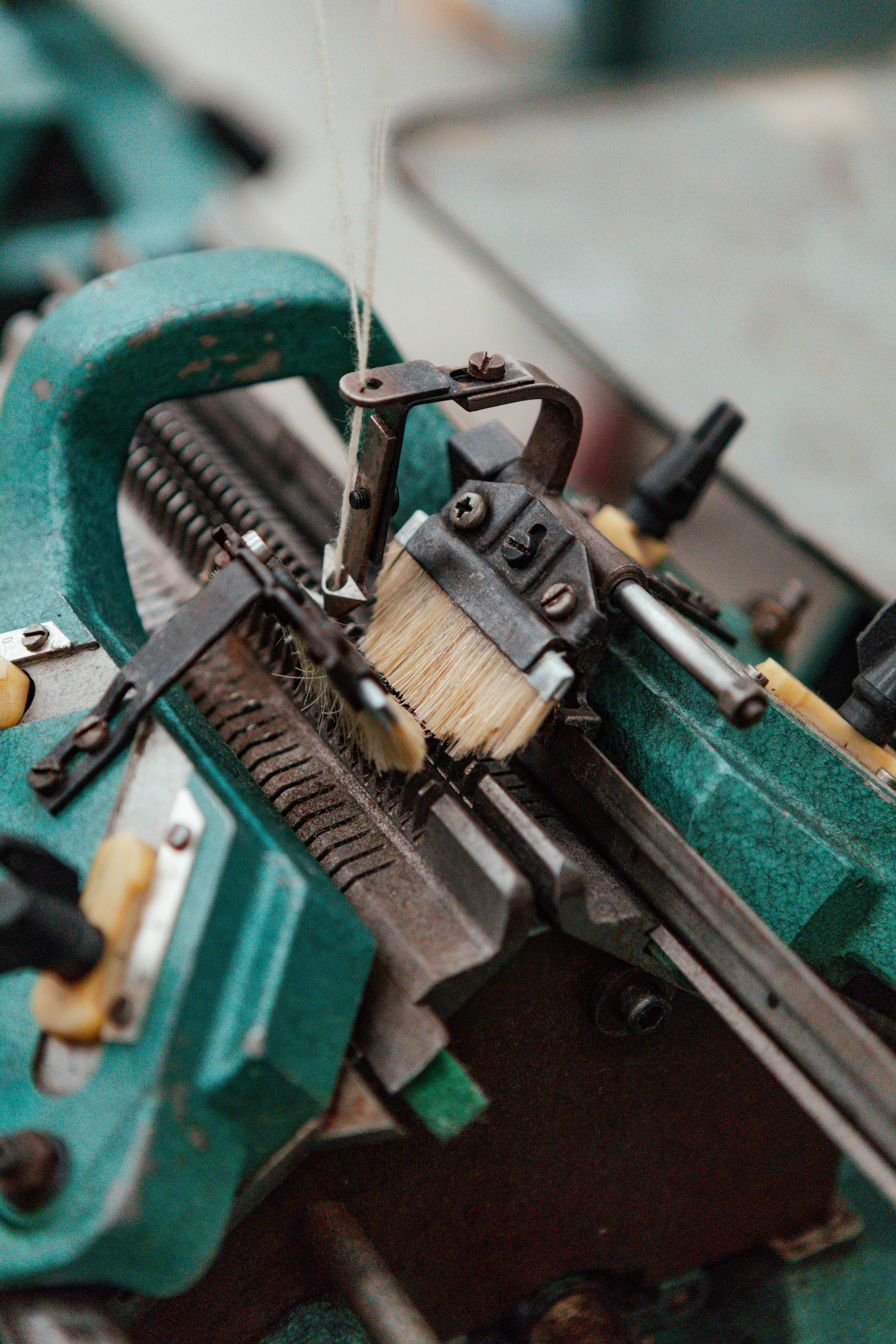 Close-up of the needle bed of a green industrial knitting machine