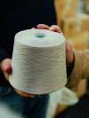 Hands holding a cone of undyed cream yarn