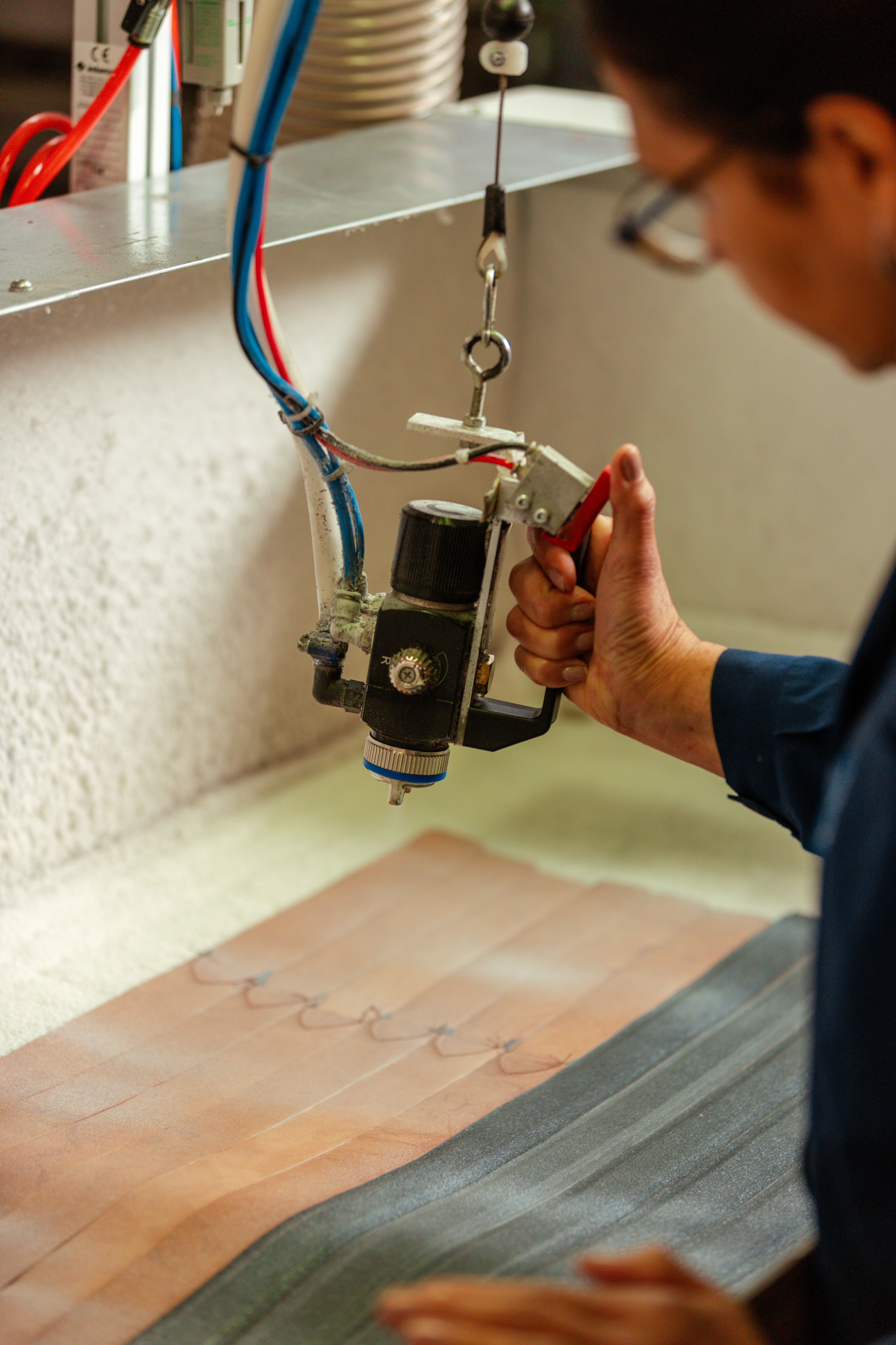 Hands guiding a leather strip through a workshop press
