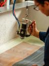 Hands guiding a leather strip through a workshop press