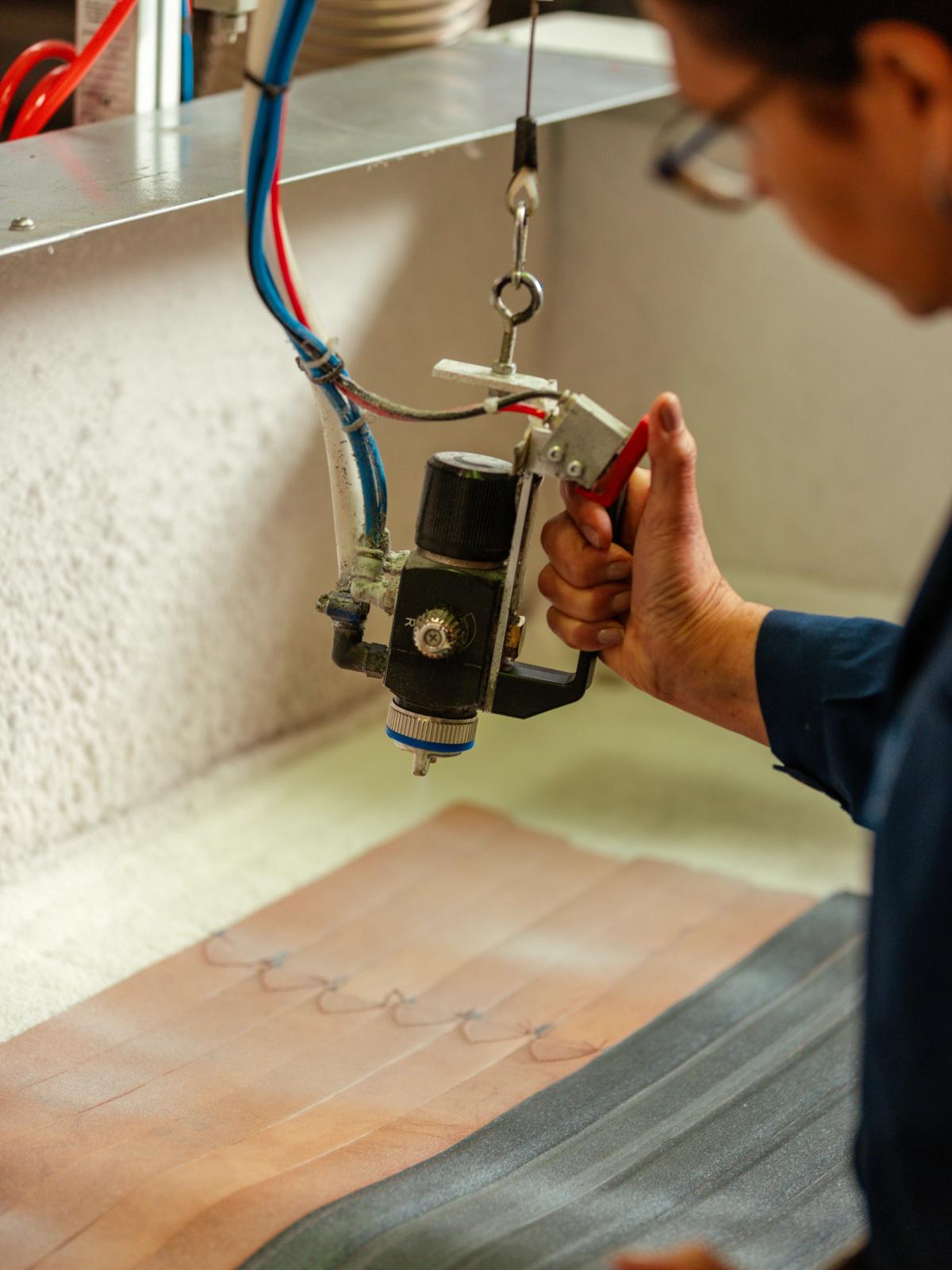 Hands guiding a leather strip through a workshop press