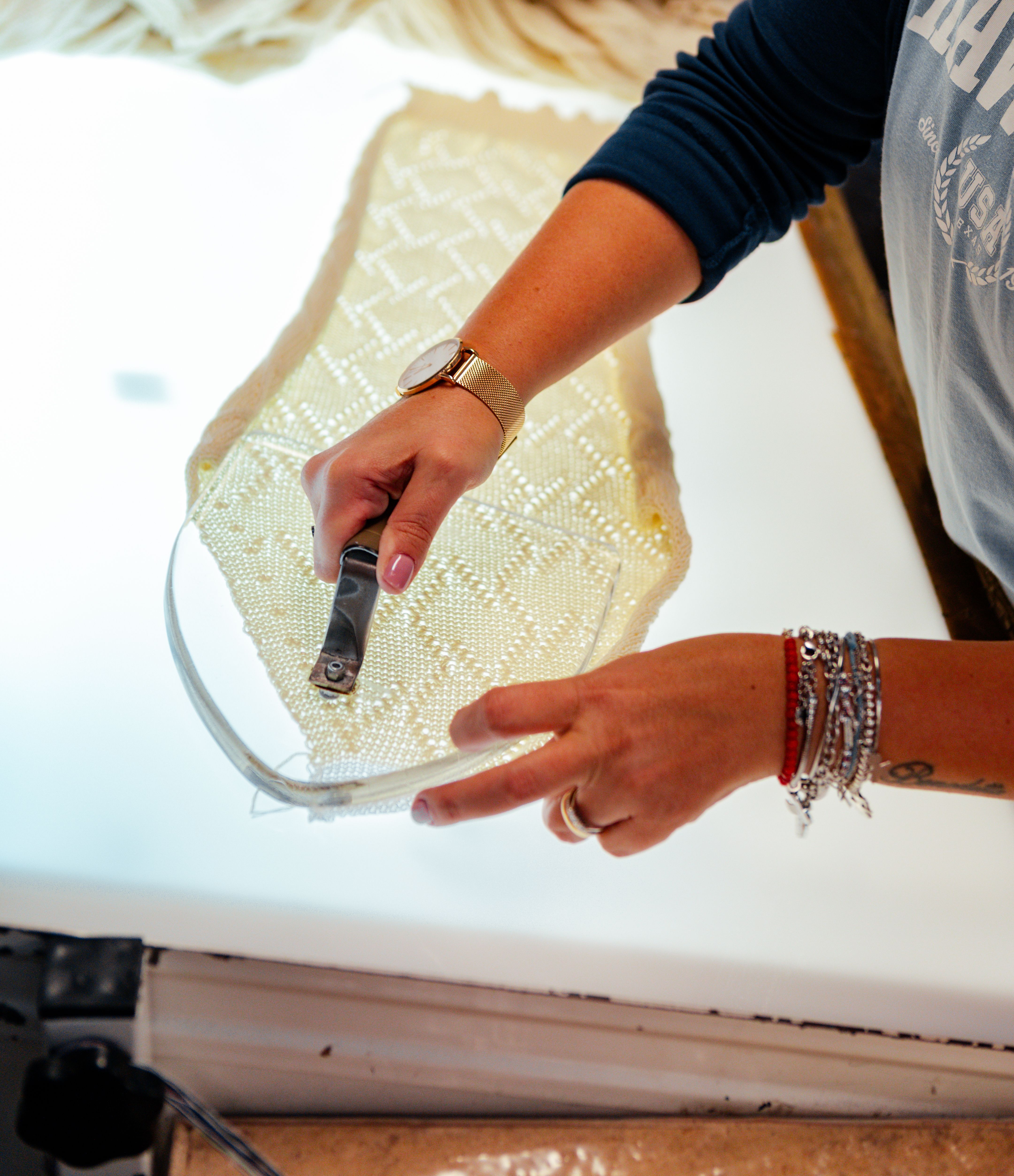Hands marking a paper garment pattern on a light table