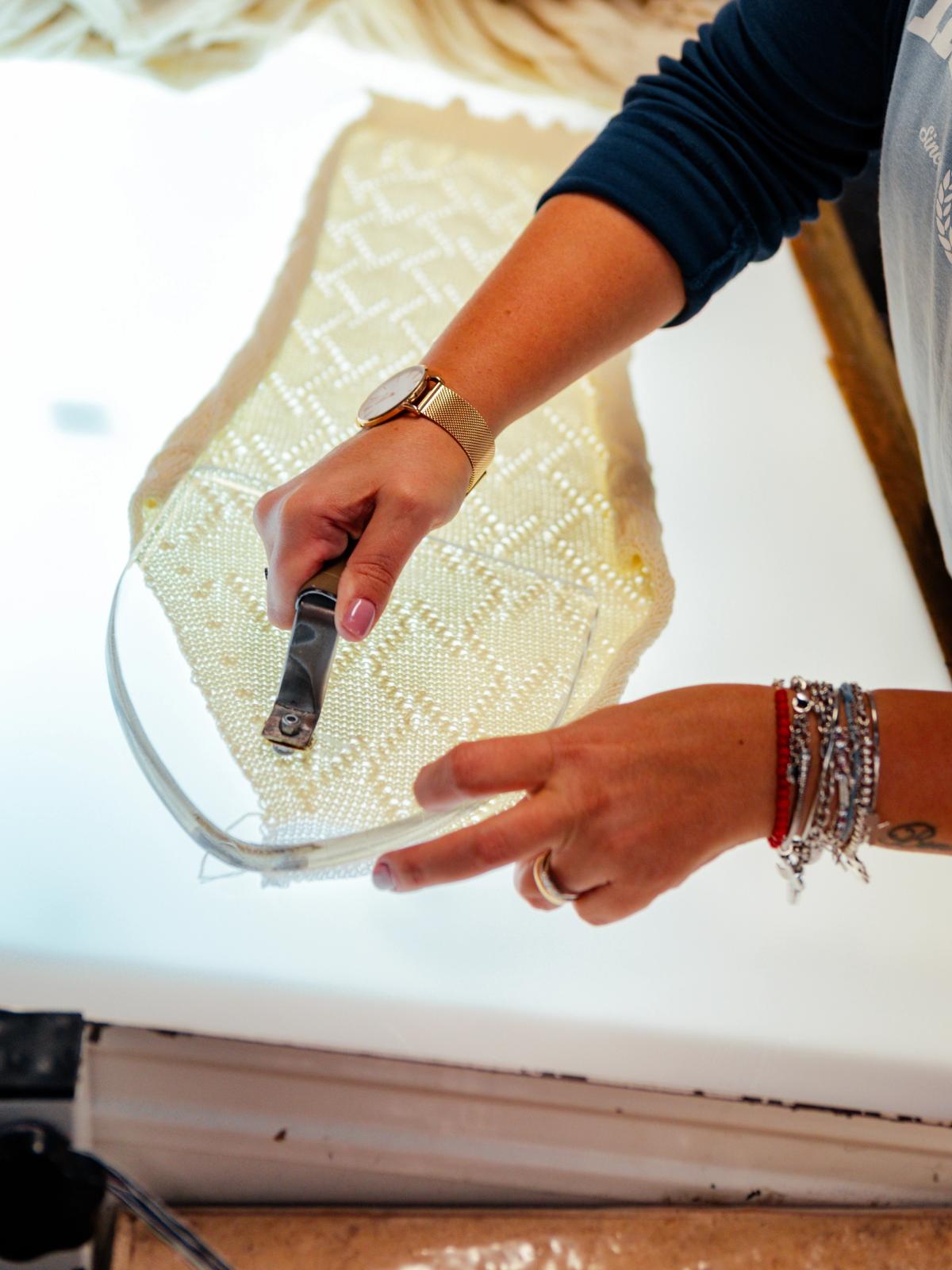 Hands marking a paper garment pattern on a light table