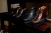 Black and brown leather boots and shoes displayed on a dark wooden shelf