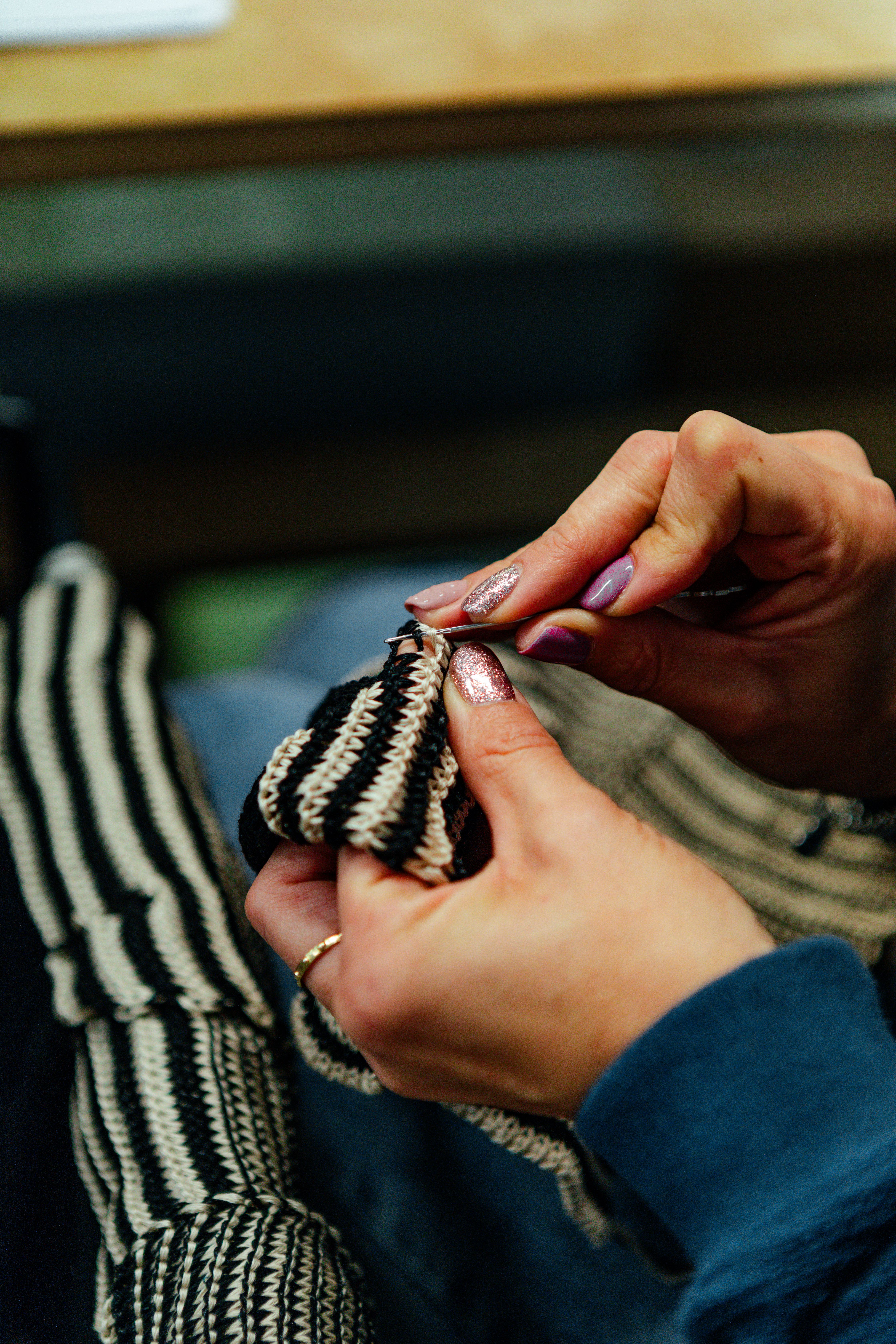 Hands finishing a blue and white striped knitted garment