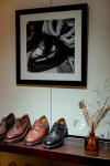 A shop display shelf of leather shoes beneath a framed black-and-white photograph