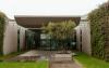 The entrance courtyard of a modern factory building with an olive tree