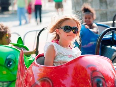Little girl with sunglasses riding the Whales Kiddie Ride at DelGrosso's Amusement Park