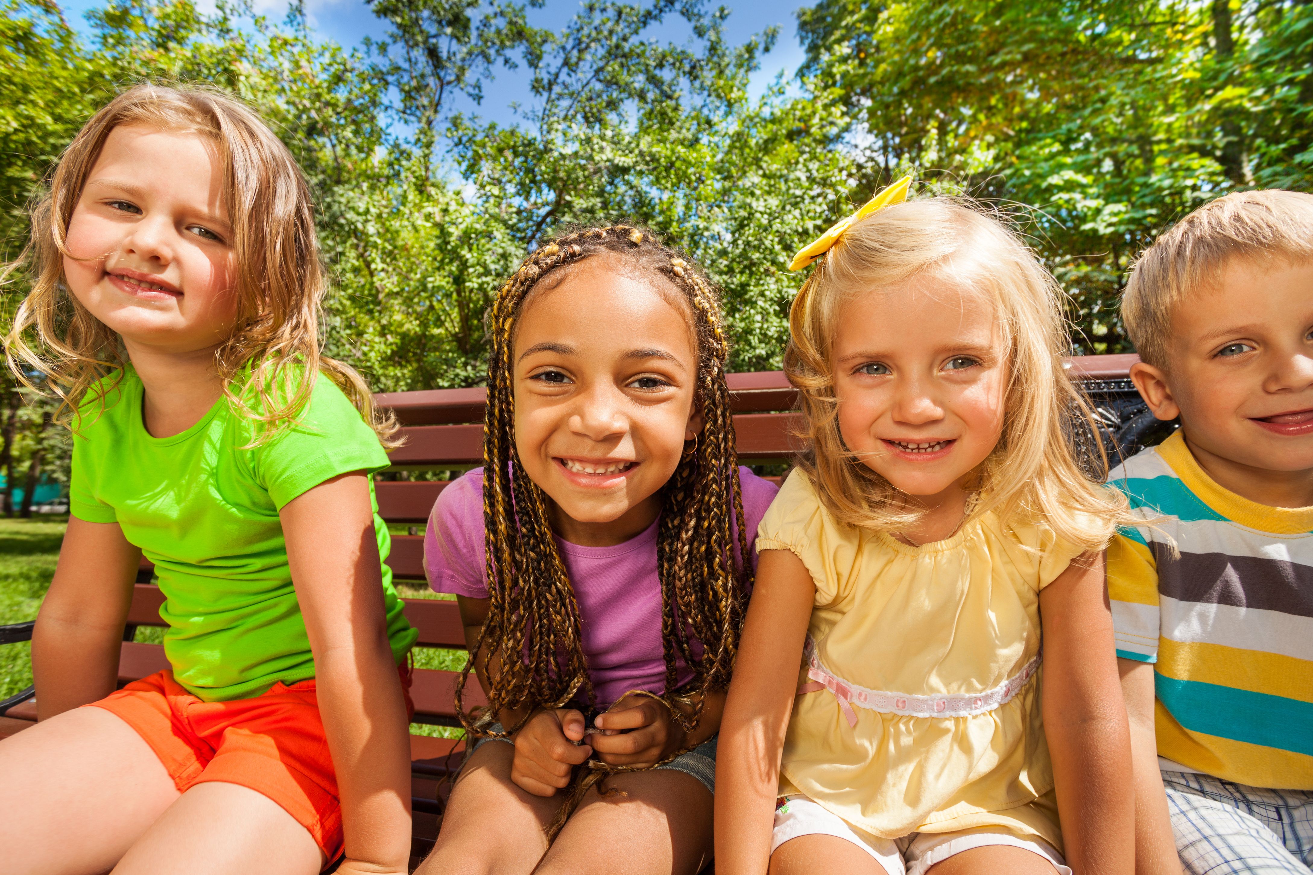 Kids sitting on a bench at the park.