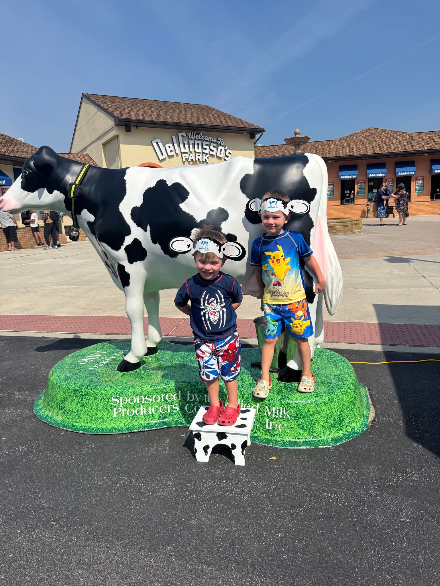 Cow statue with two children in front of it.