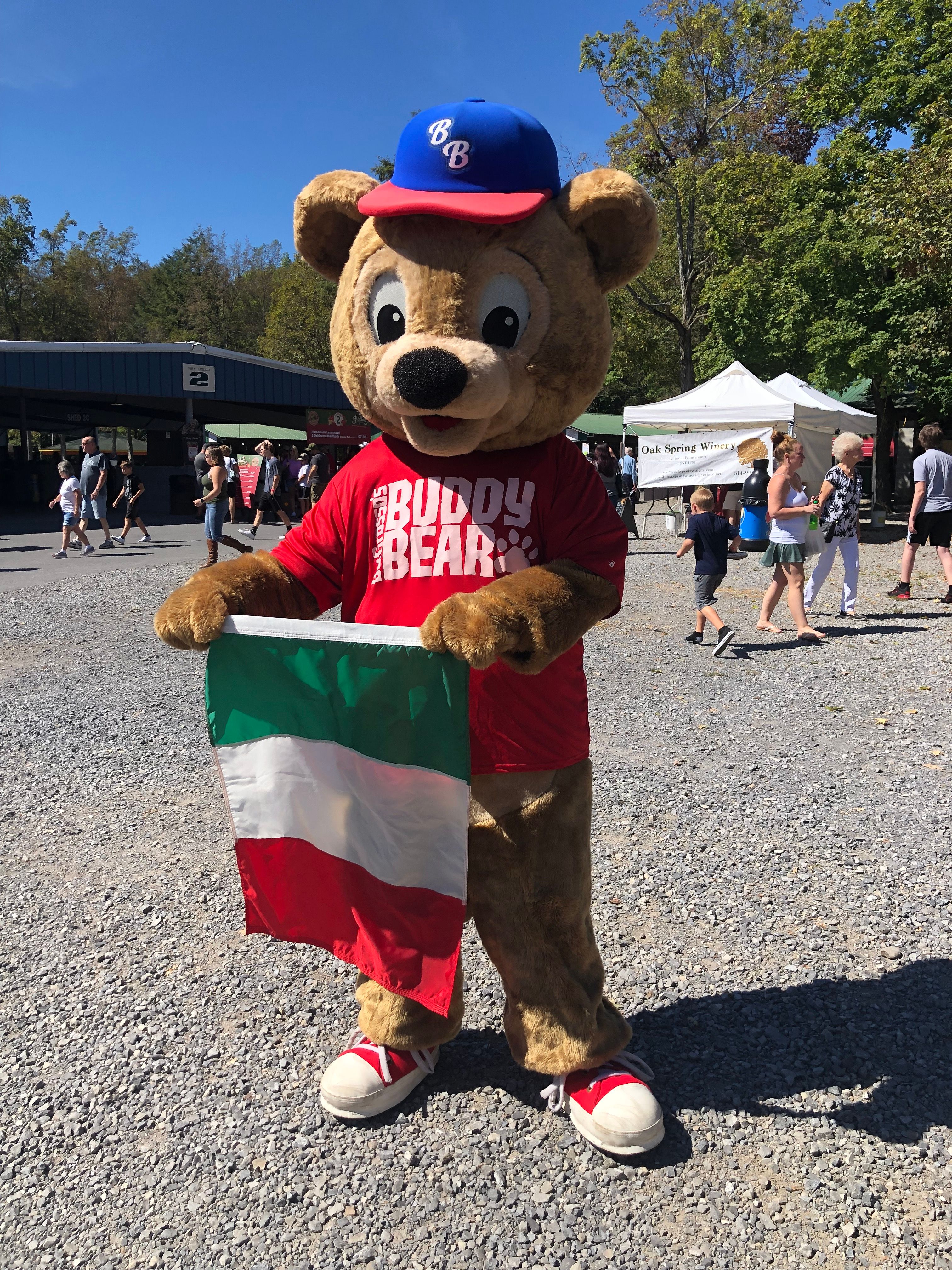 DelGrosso's Park Mascot Buddy Bear holding an Italian Flag in the park.