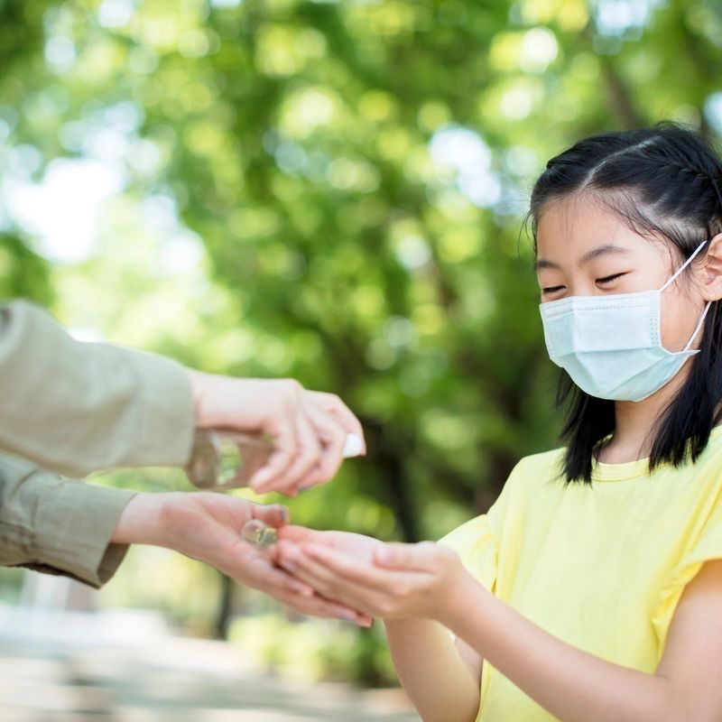 Small girl getting hand sanitizer from an adult