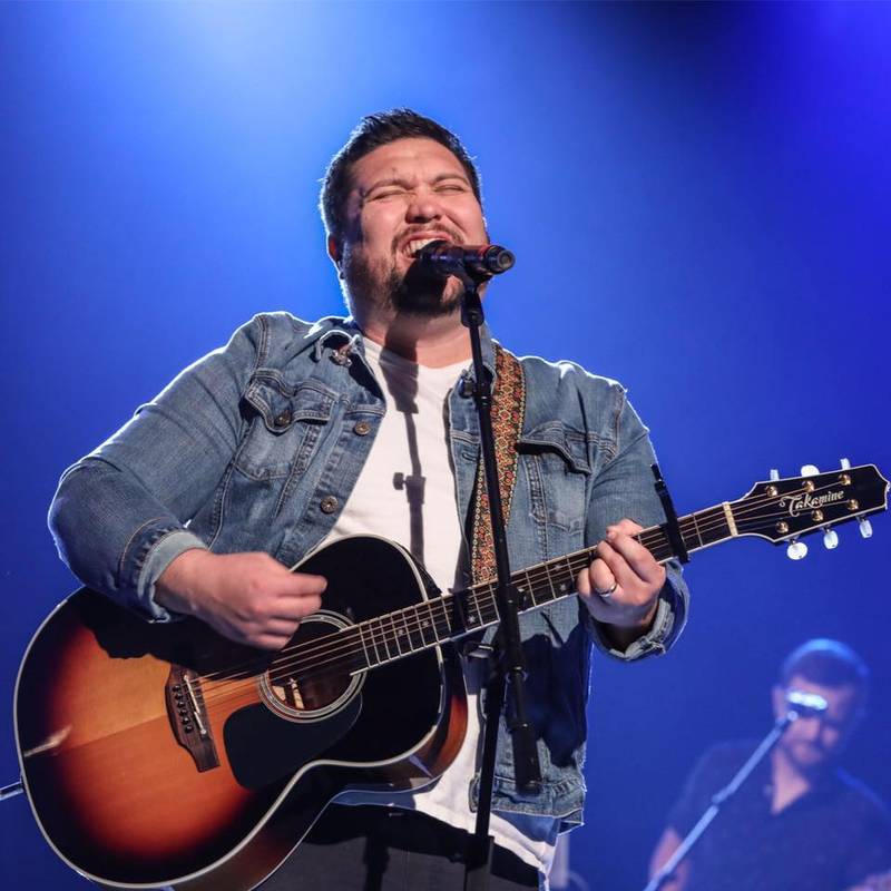 Micah Tyler performing on a stage with a guitar.