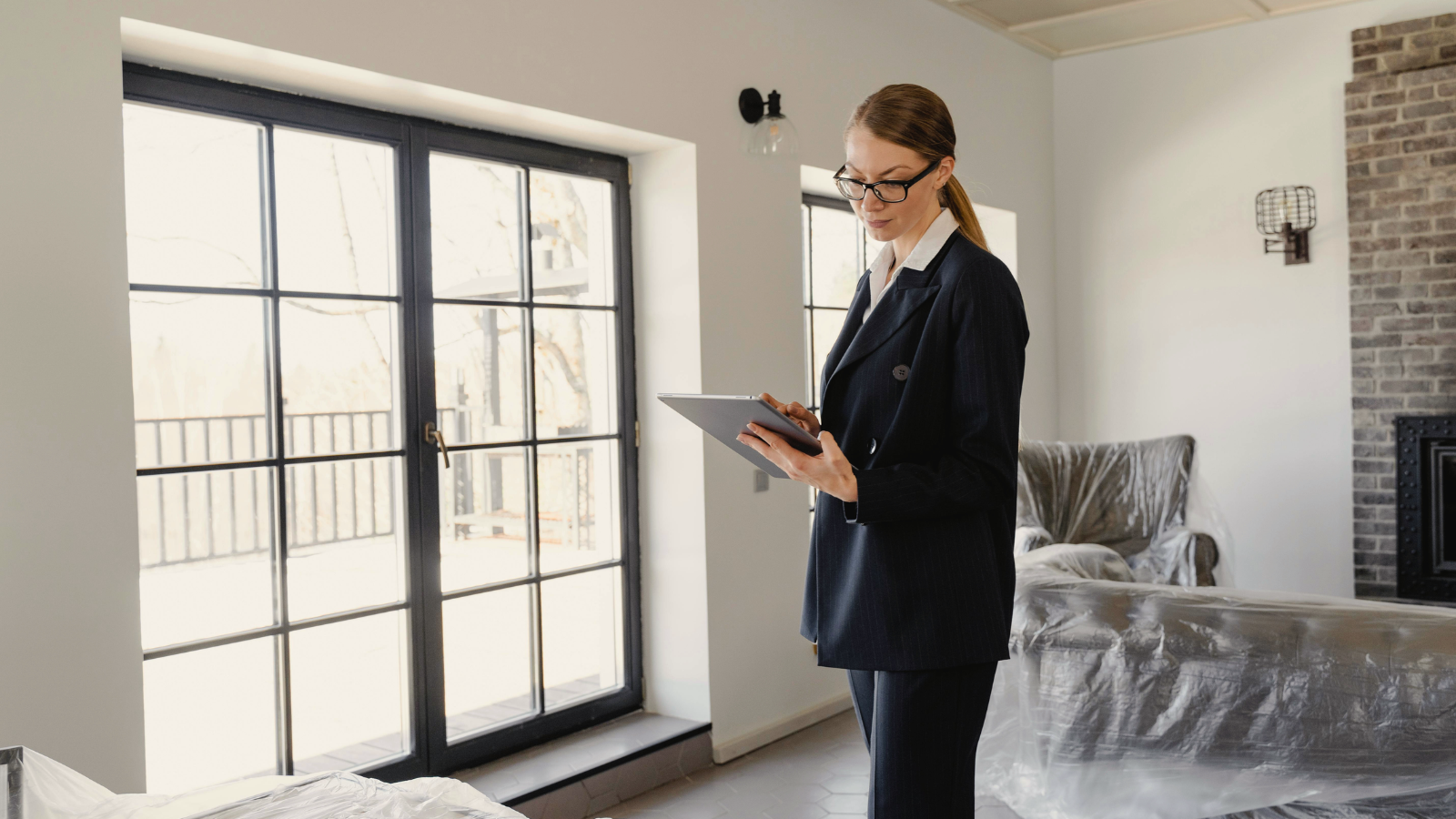 Property manager in business attire, holding a tablet and reviewing maintenance needs in the living room