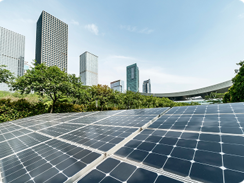 Solar panels with a city skyline and greenery in the background
