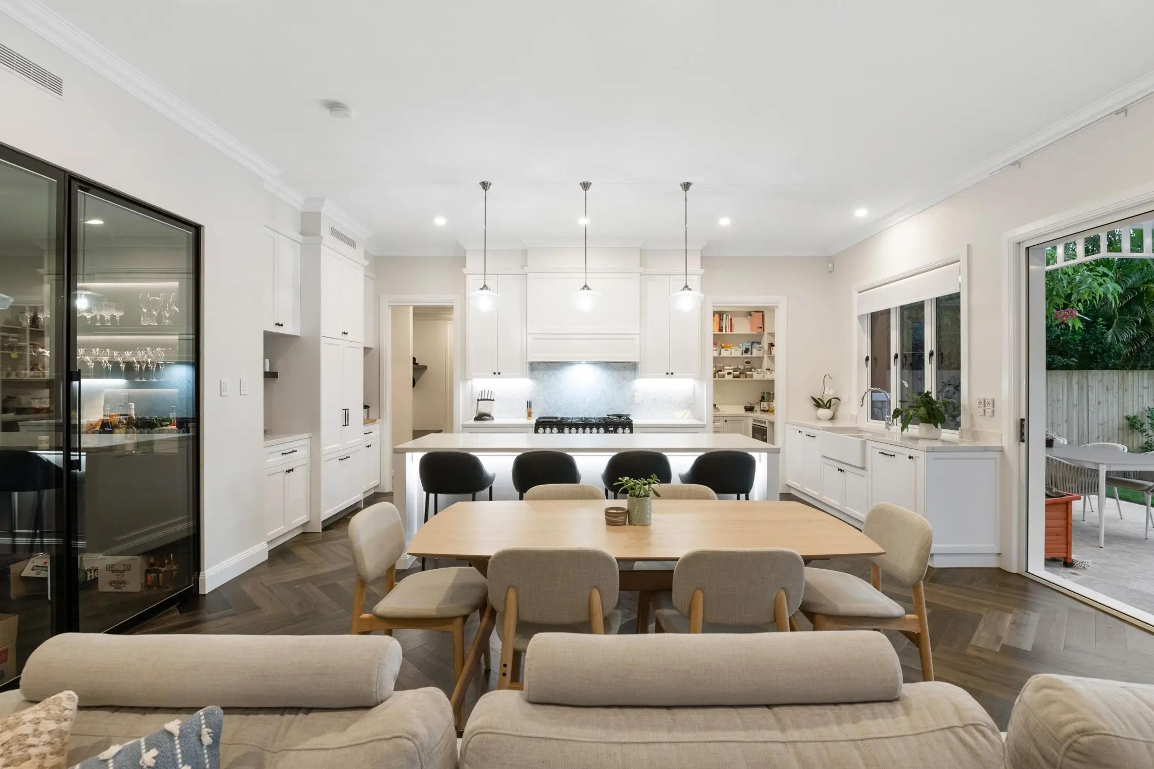 White kitchen with island bench and dining table