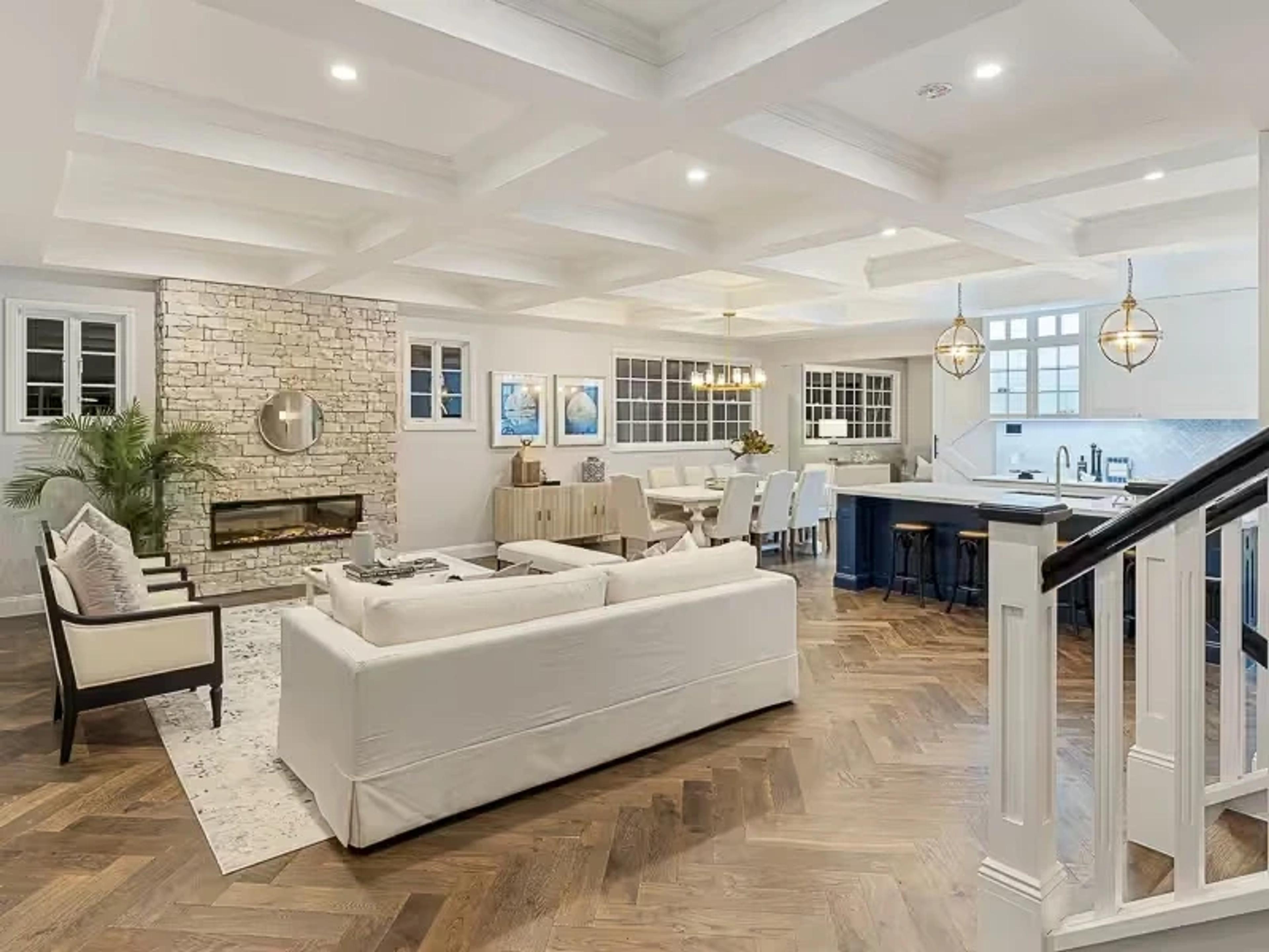 Open plan living room with stone fireplace and kitchen beyond