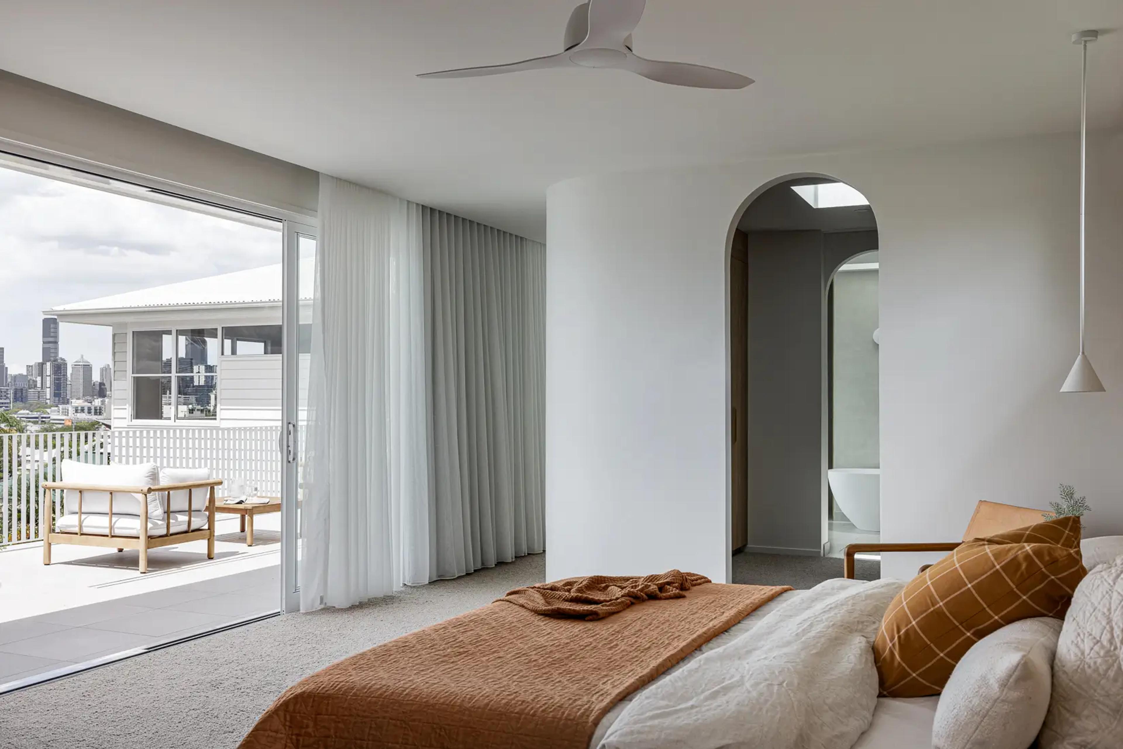 Bedroom opening to balcony with distant city skyline