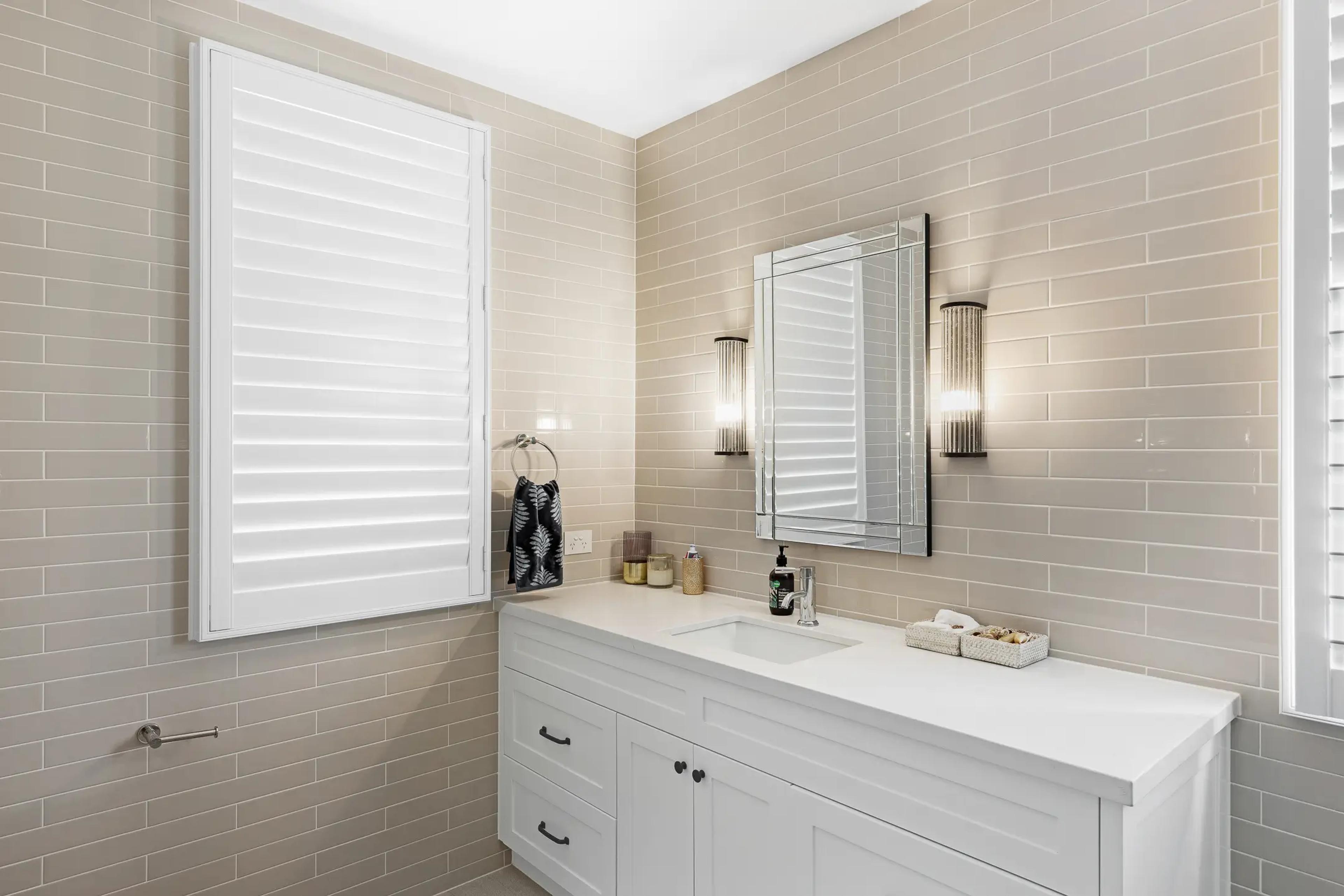 Bathroom with beige tiled walls and white vanity