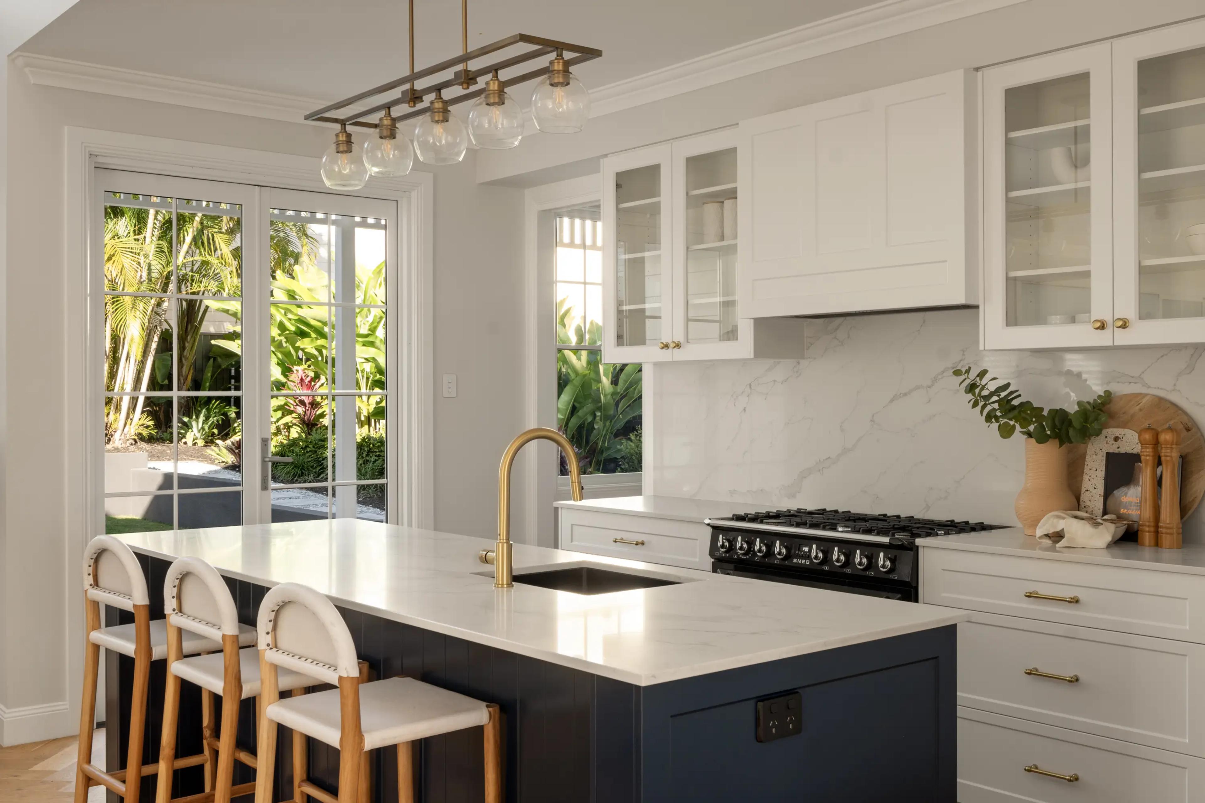 Kitchen island with brass tap, navy cabinetry and gas cooktop
