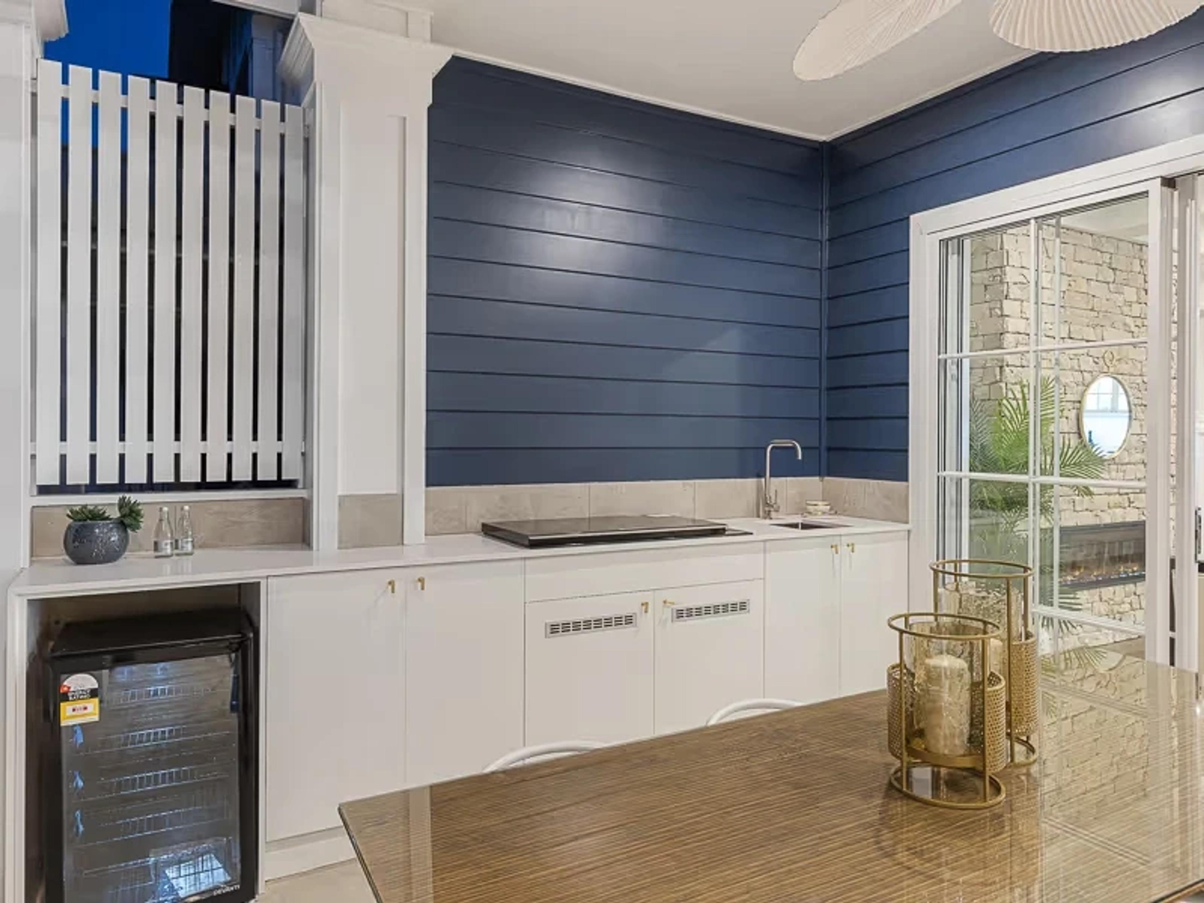 Outdoor kitchen with navy walls, cooktop and bar fridge