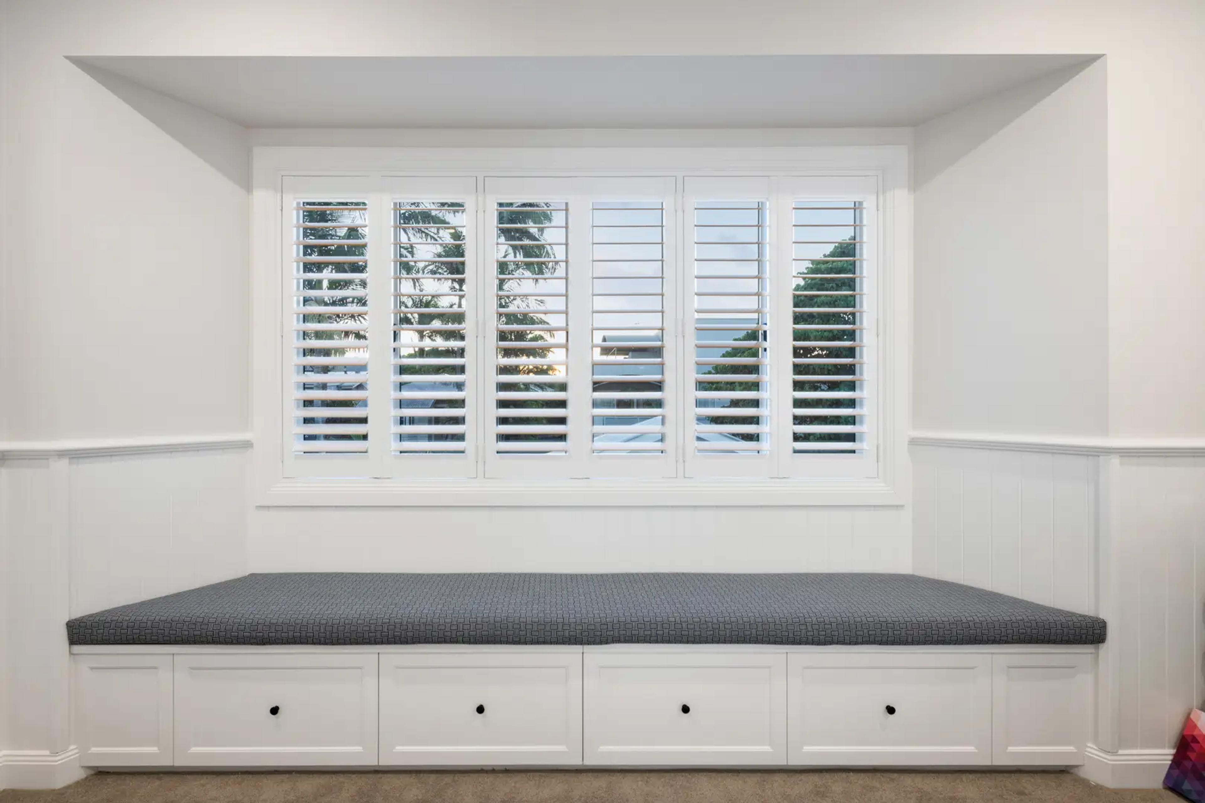 Window seat below plantation shutters with drawer storage