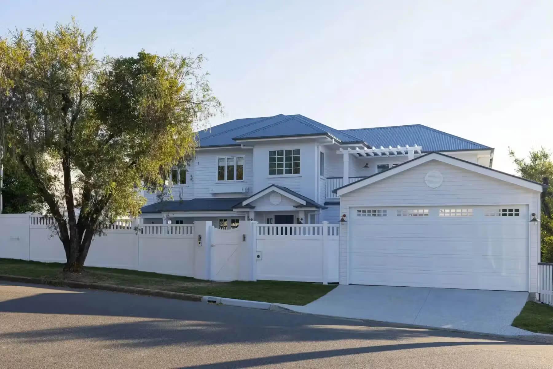 Street frontage of a Hamptons-style home renovation with white fence and double garage in Hendra by Invilla Architecture