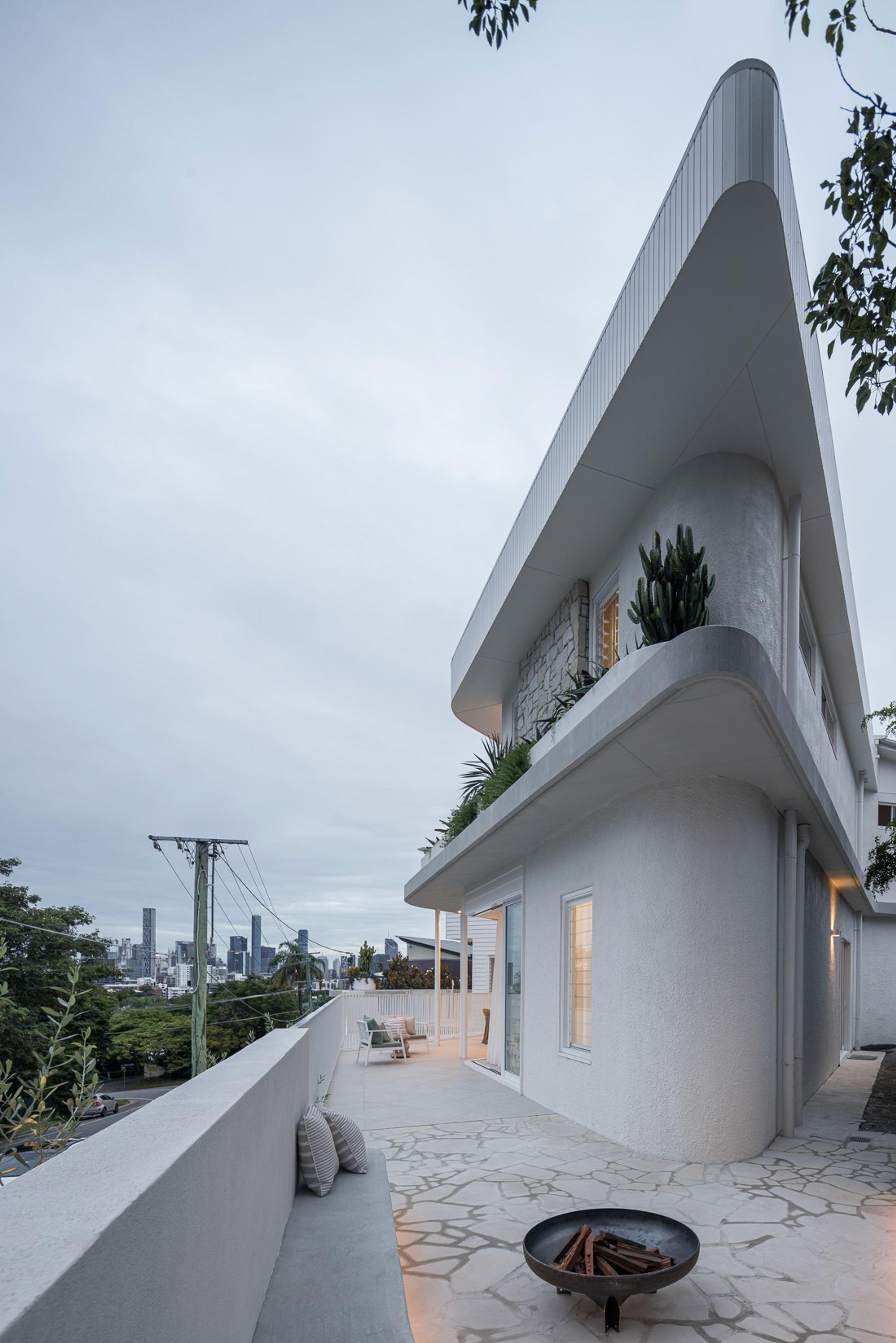 Curved white facade over terrace with distant city view