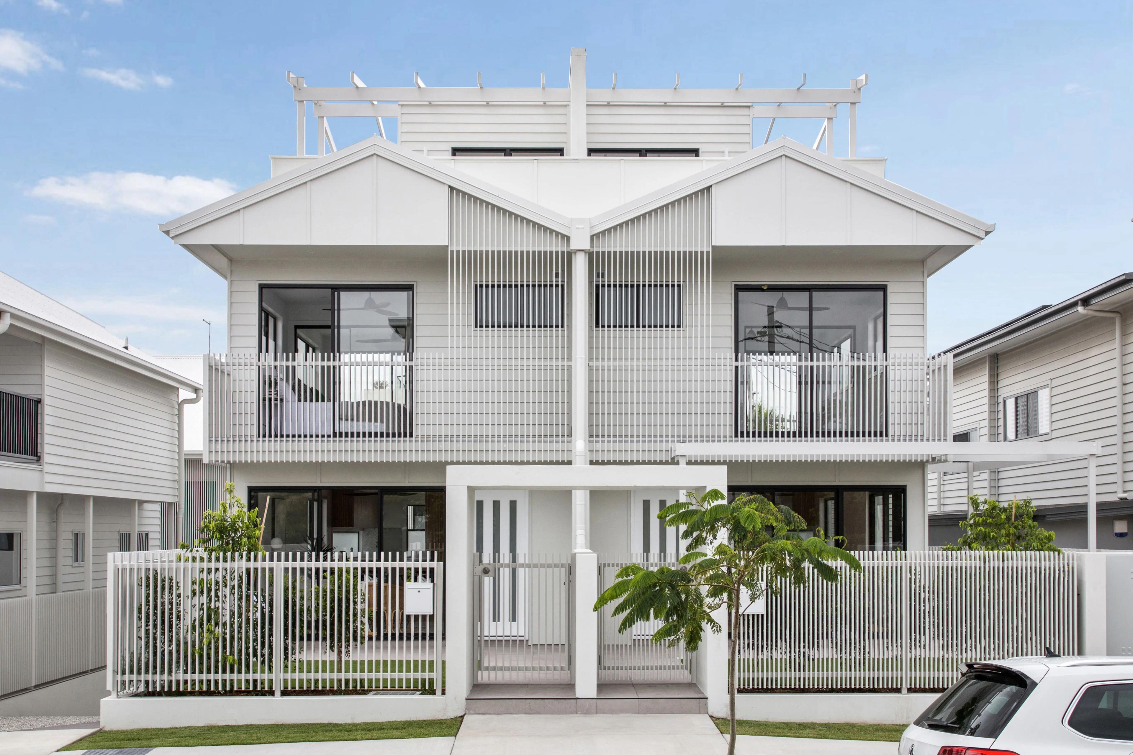 White weatherboard townhouses street facade with picket fencing and balconies