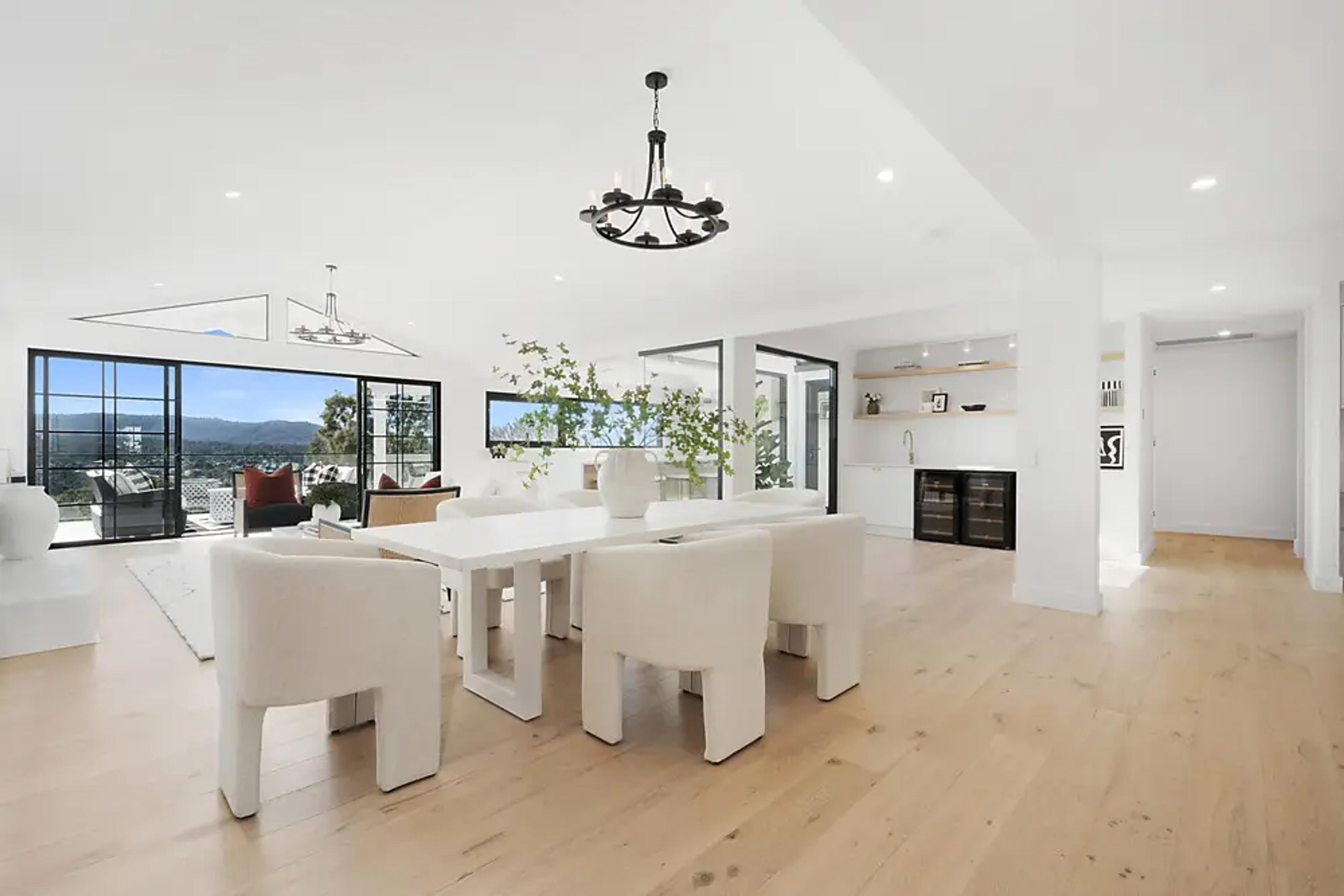Open dining area with white table, chandelier and built-in bar.