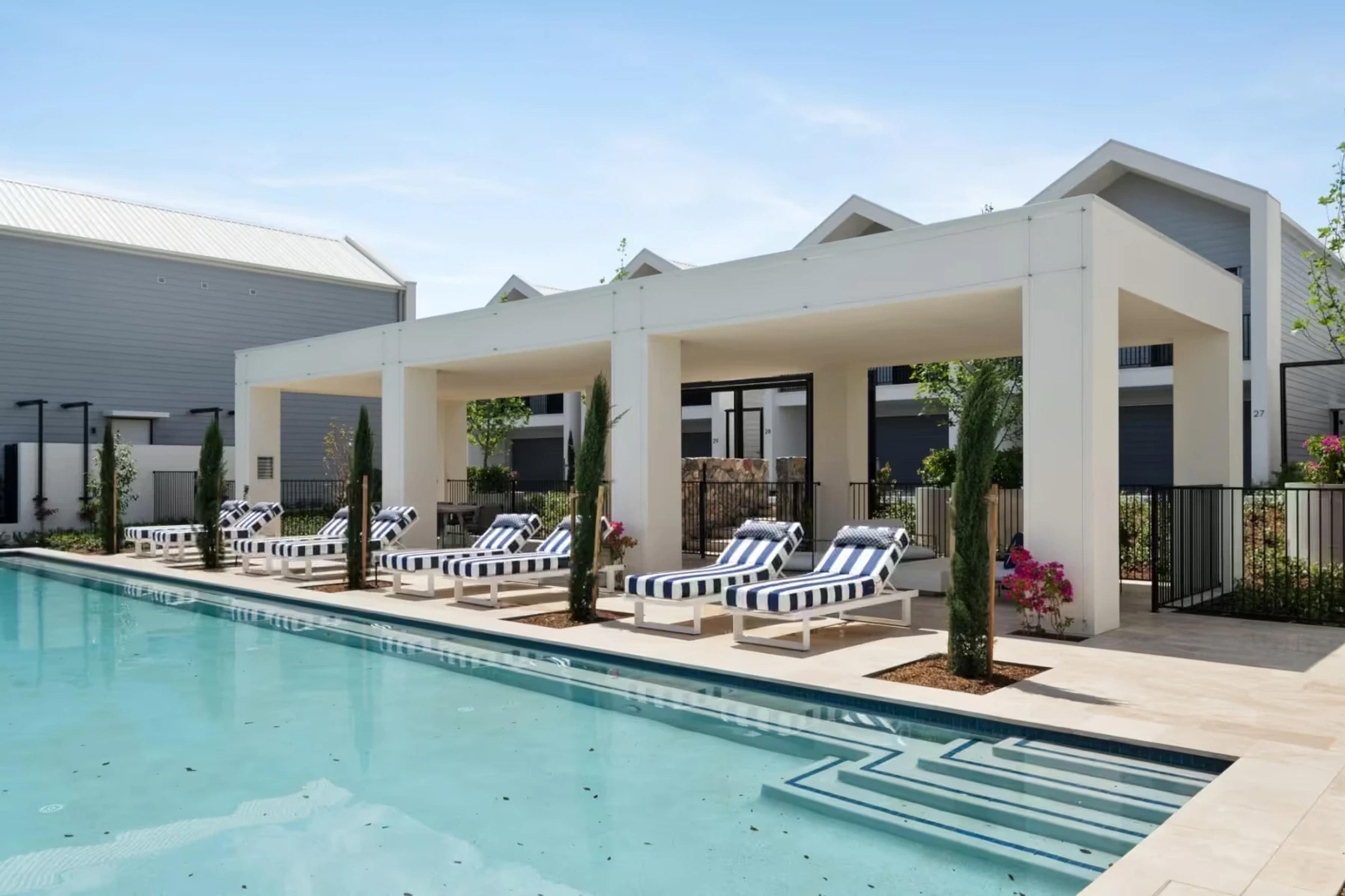 Poolside cabana with striped loungers and townhouses behind