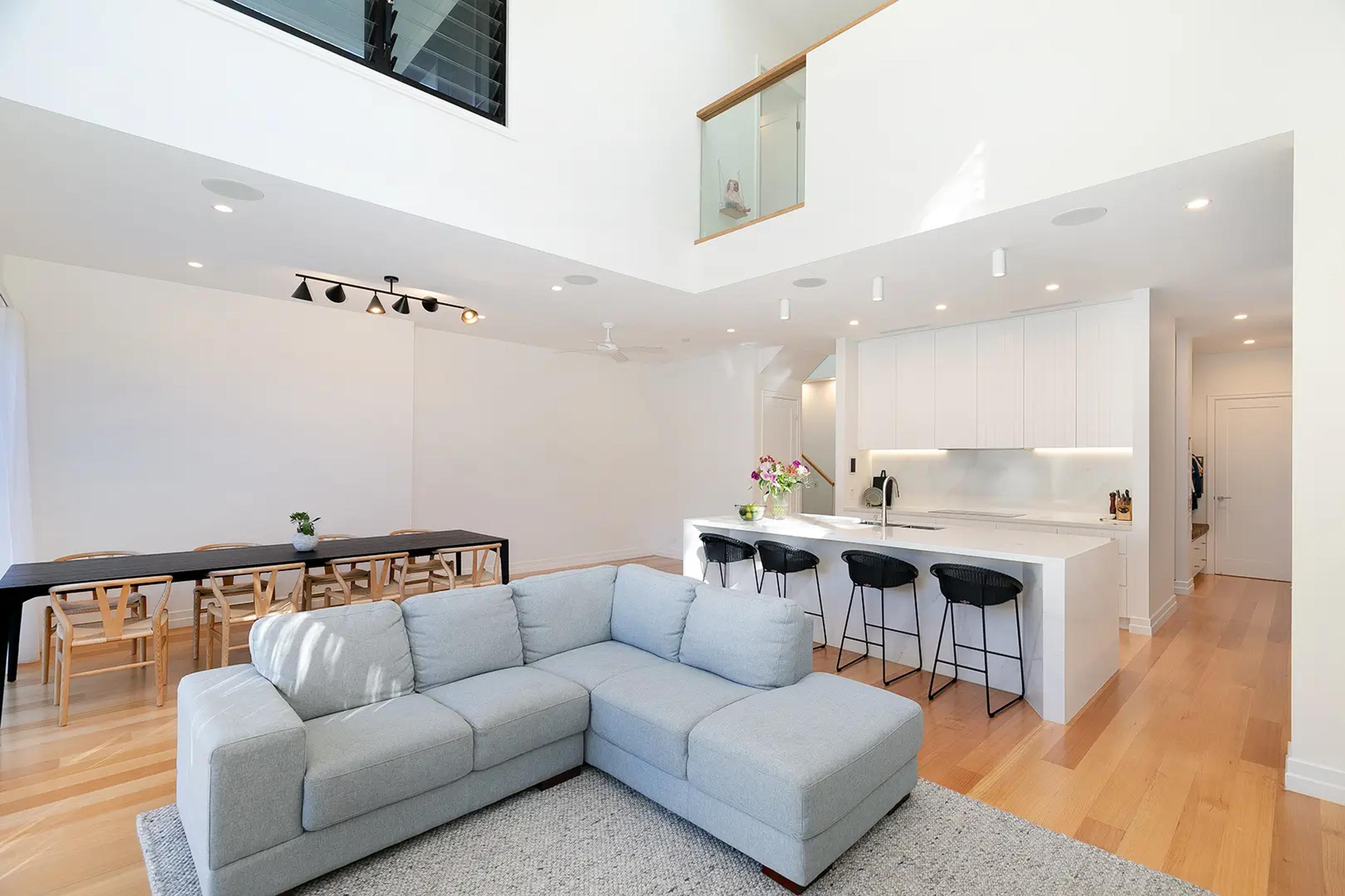 Open plan living room, dining area and white kitchen with void above