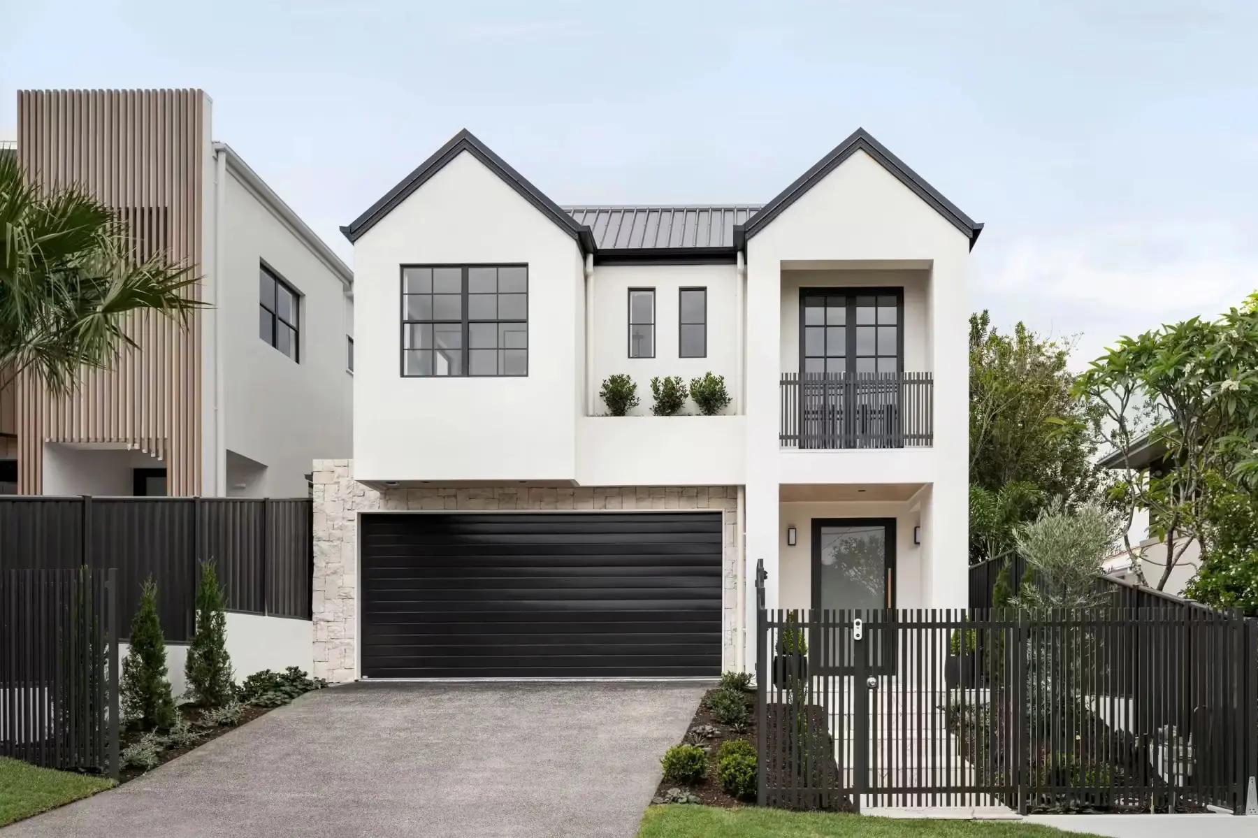 Elevated, modern coastal architecture in Australia, featuring textured white render, a natural stone facade base, and contemporary vertical fencing.