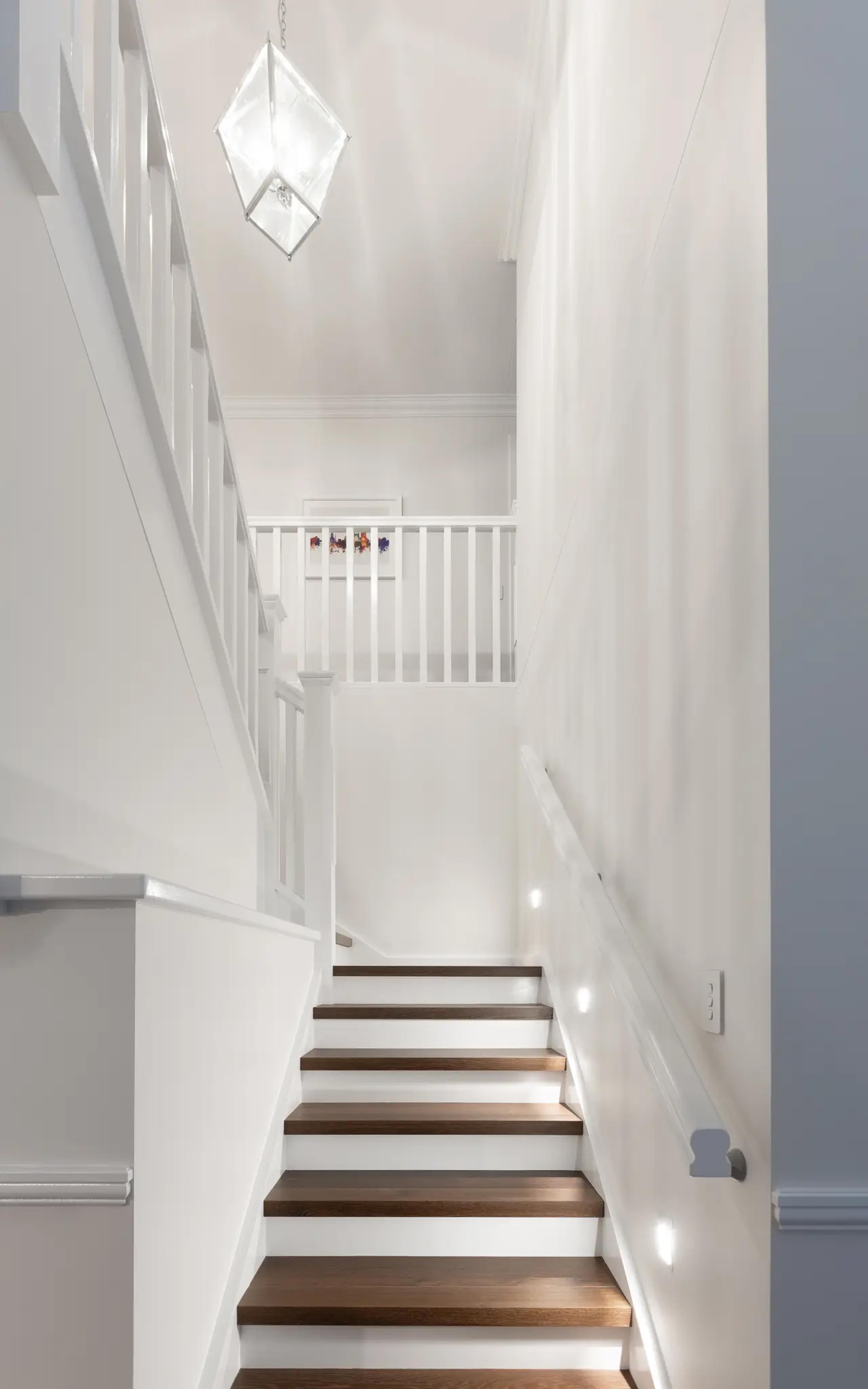 Bright staircase with timber treads, white balustrade and glass pendant light