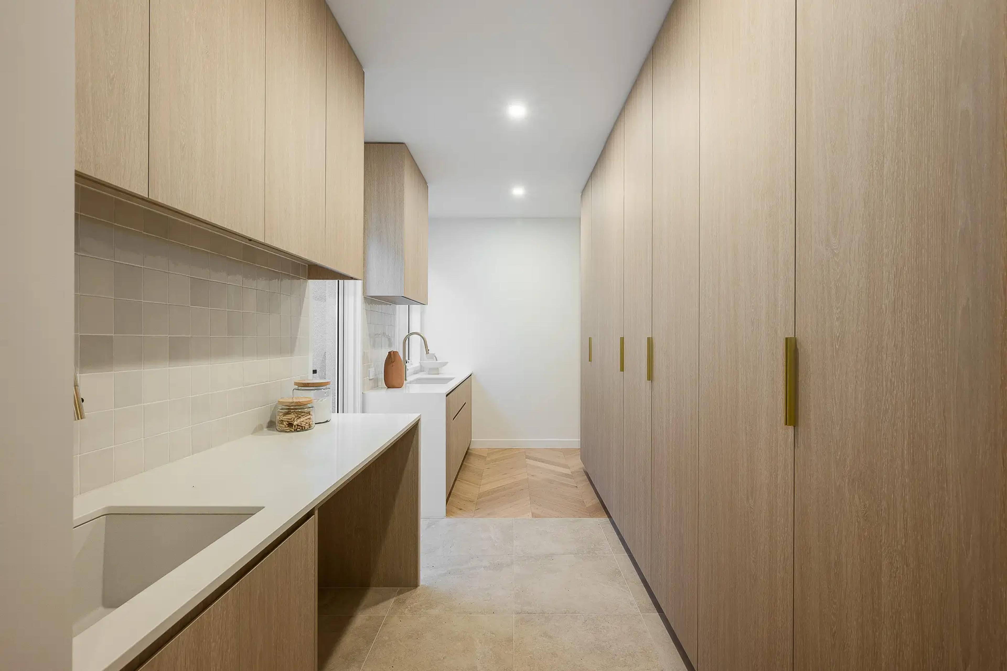 Galley laundry with timber cabinetry and stone bench
