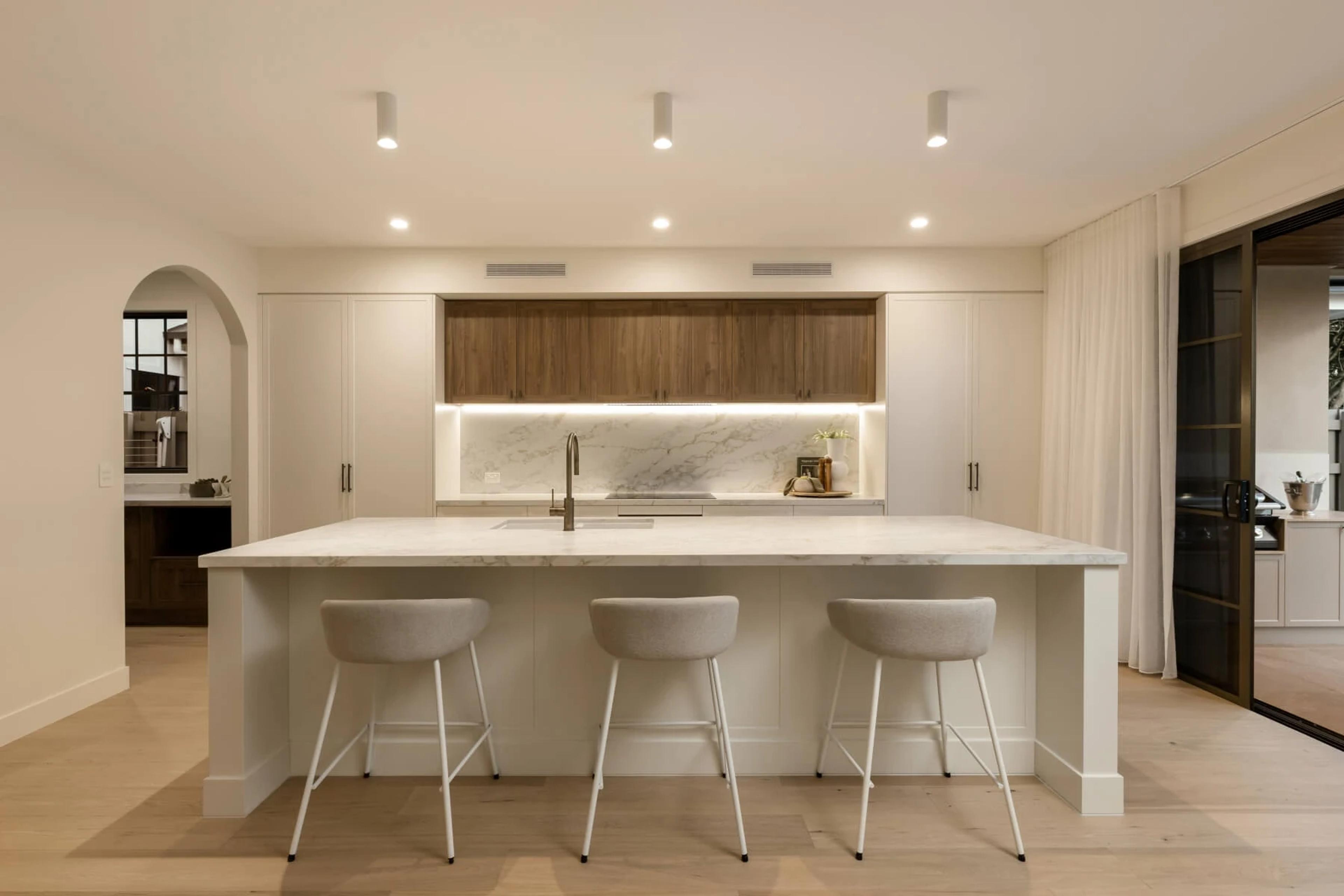 Open kitchen with large island bench and three upholstered stools
