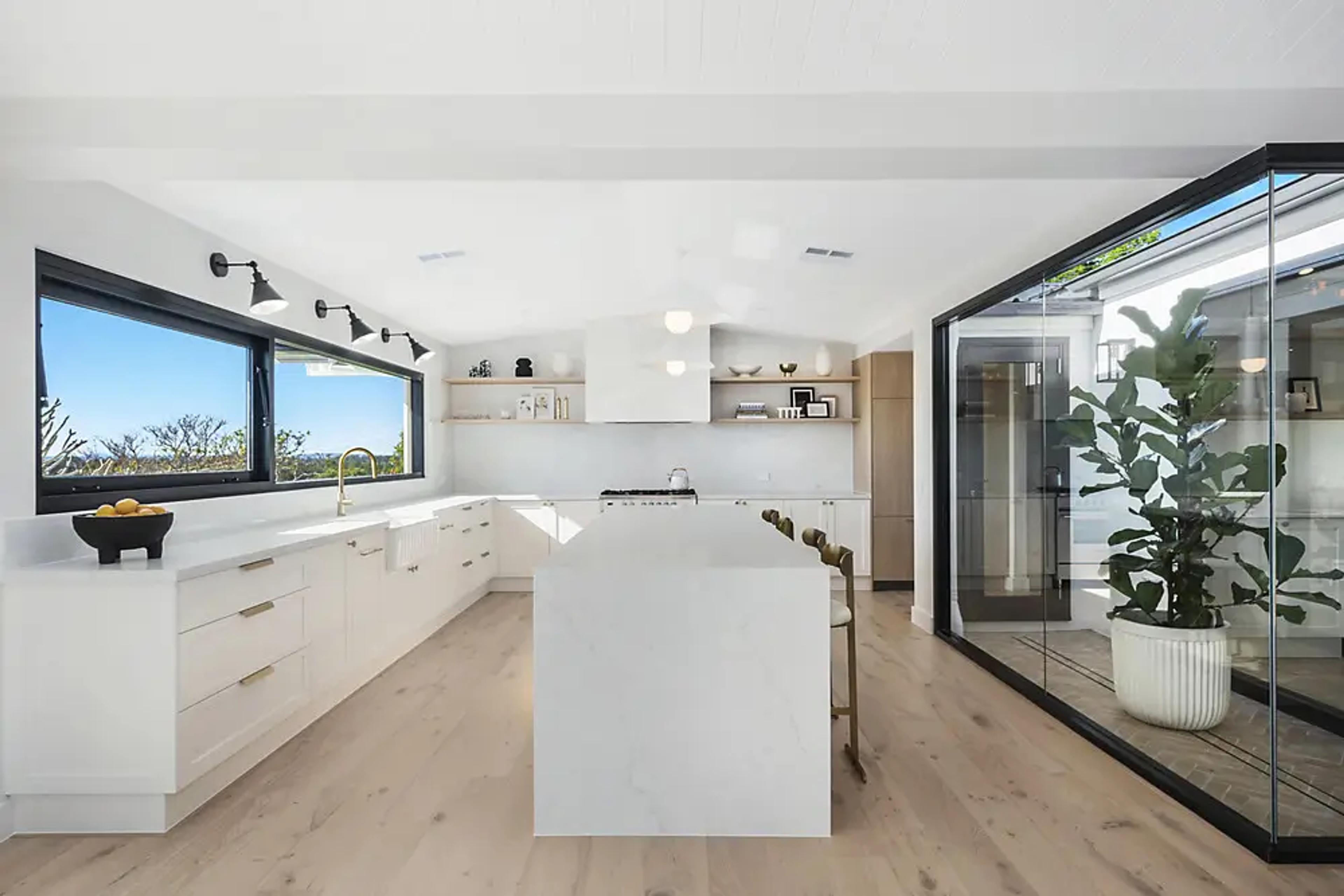 White kitchen with stone island bench and timber floors.