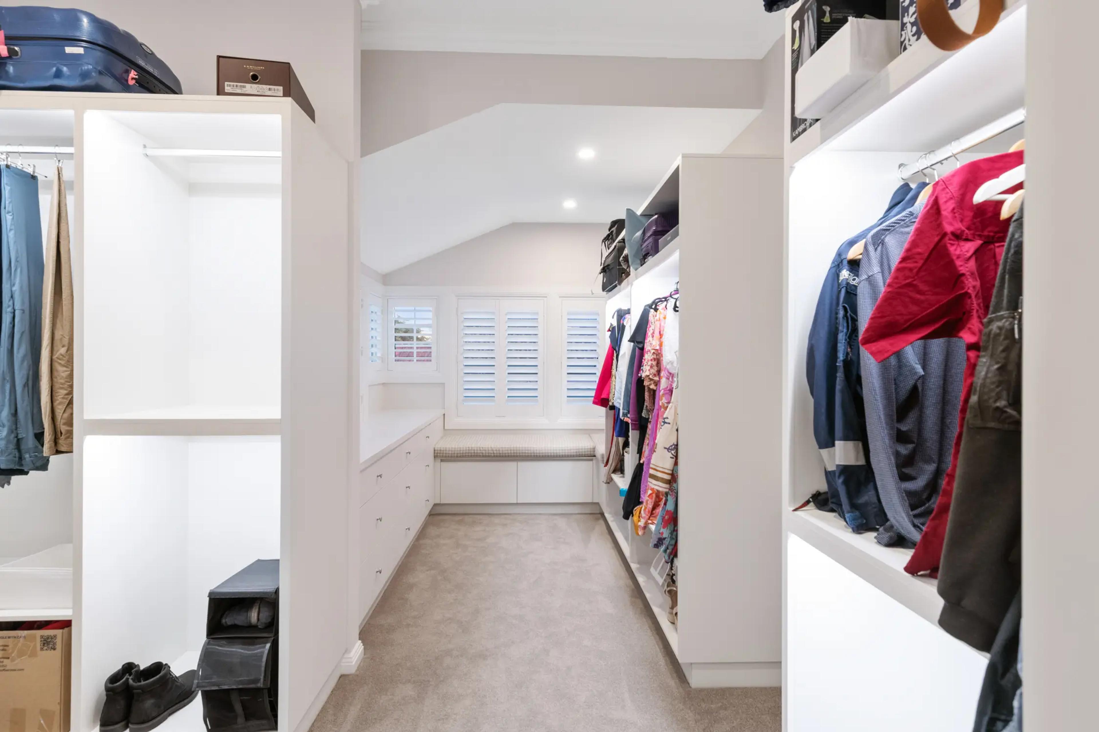 Walk in wardrobe with hanging clothes and shelving