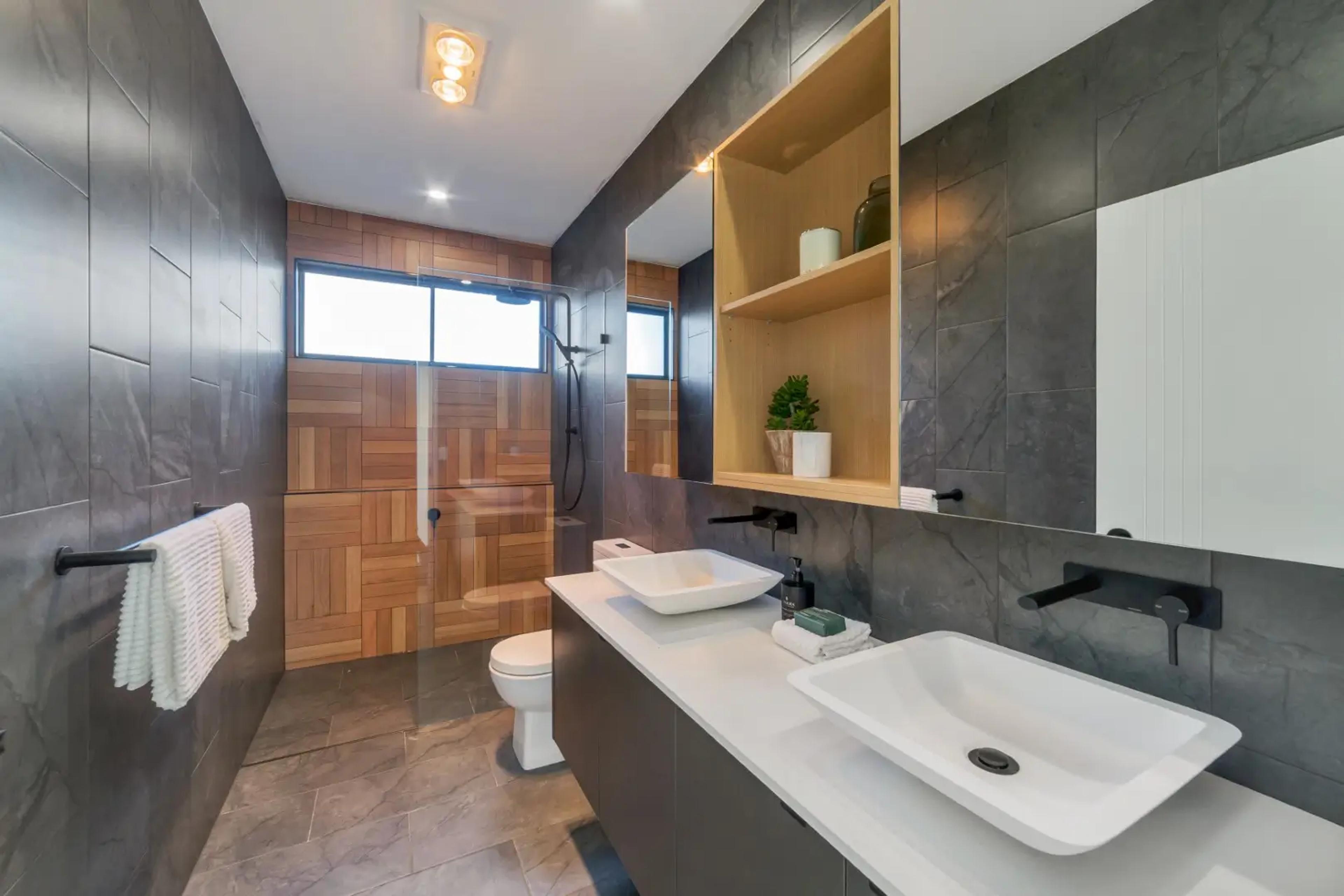 Bathroom with timber tiled shower, dark walls and vanity basin