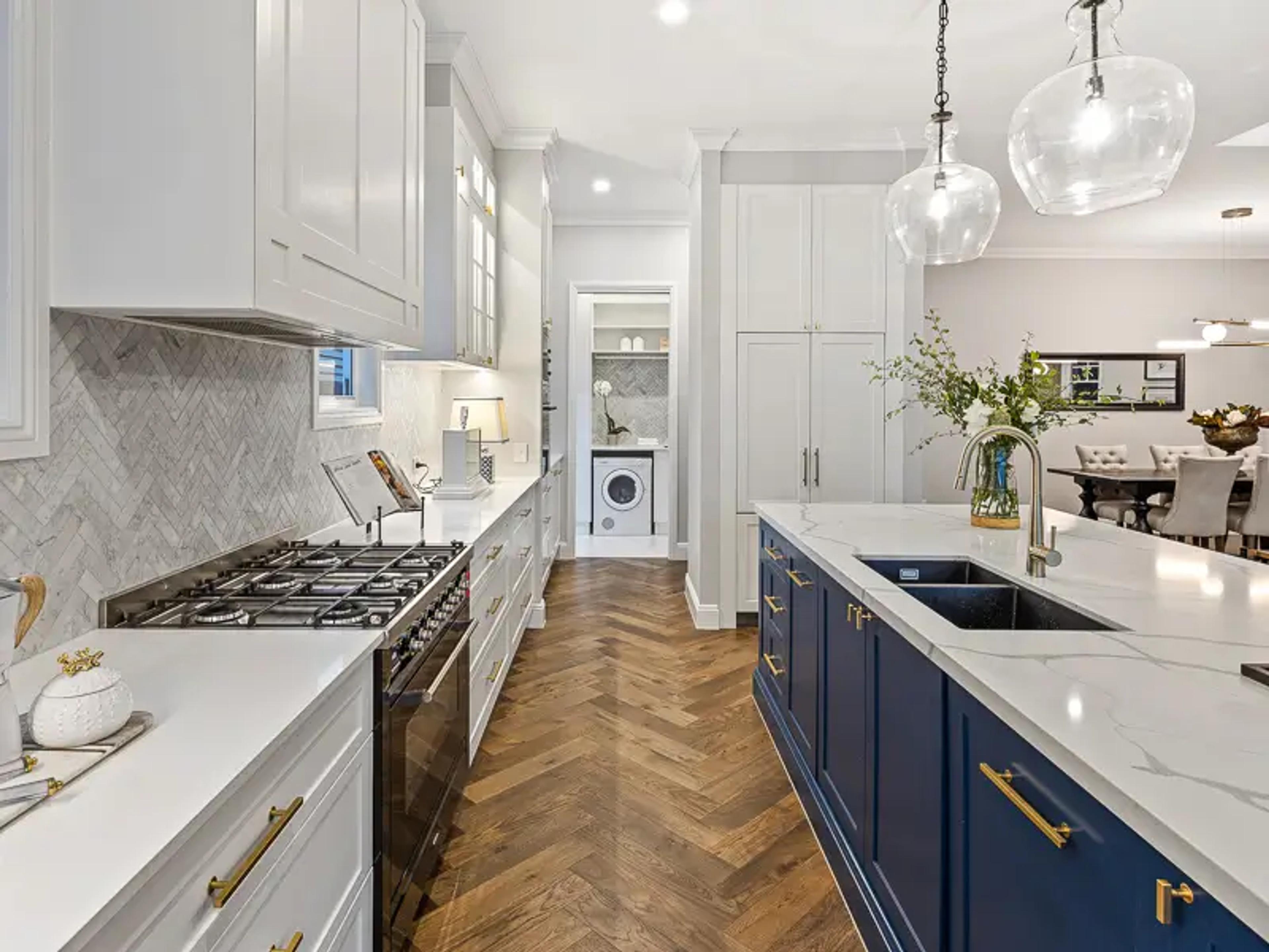 Galley kitchen with blue island bench and hidden laundry beyond