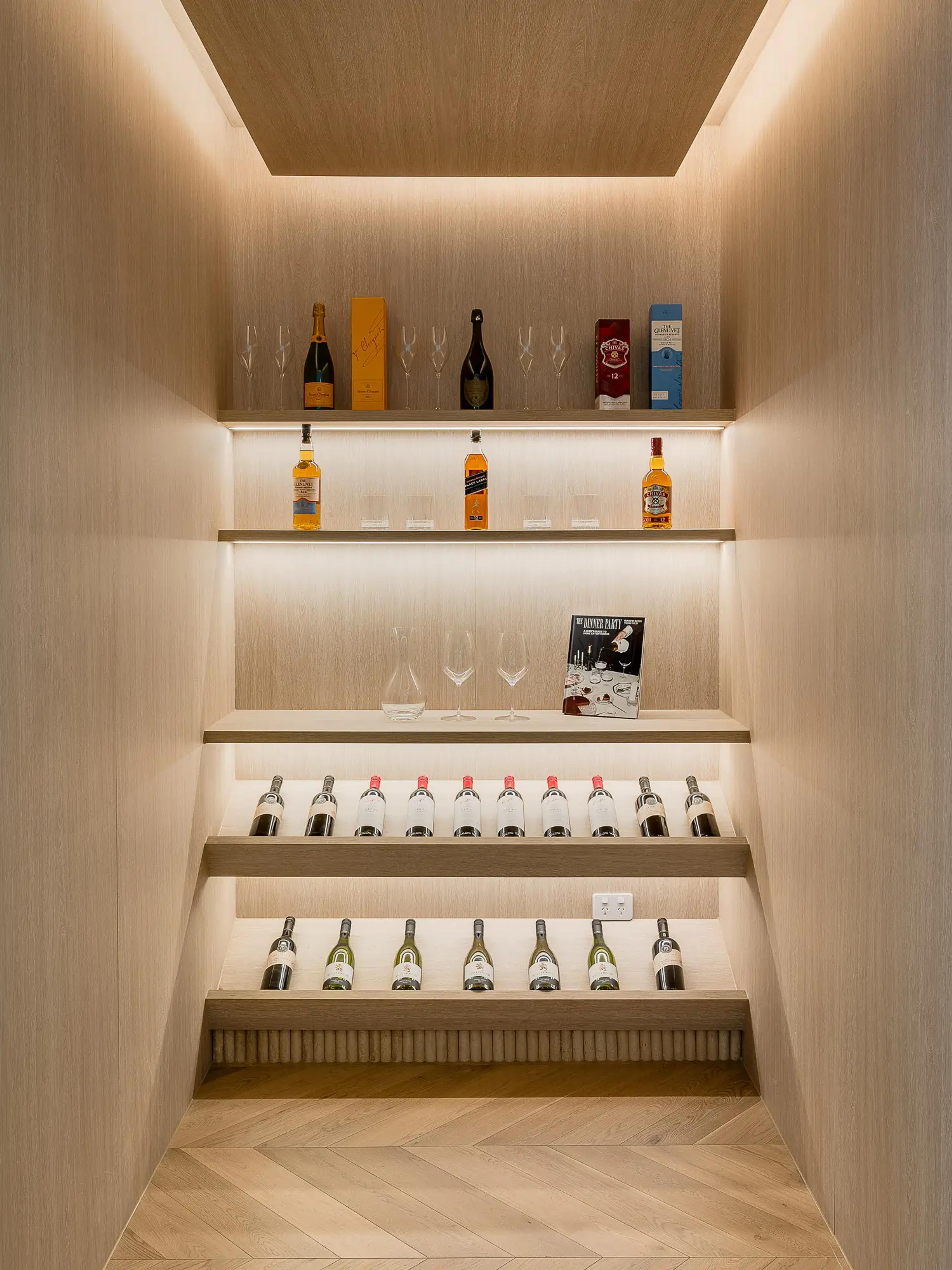 Lit wine cellar with shelved bottles and glassware