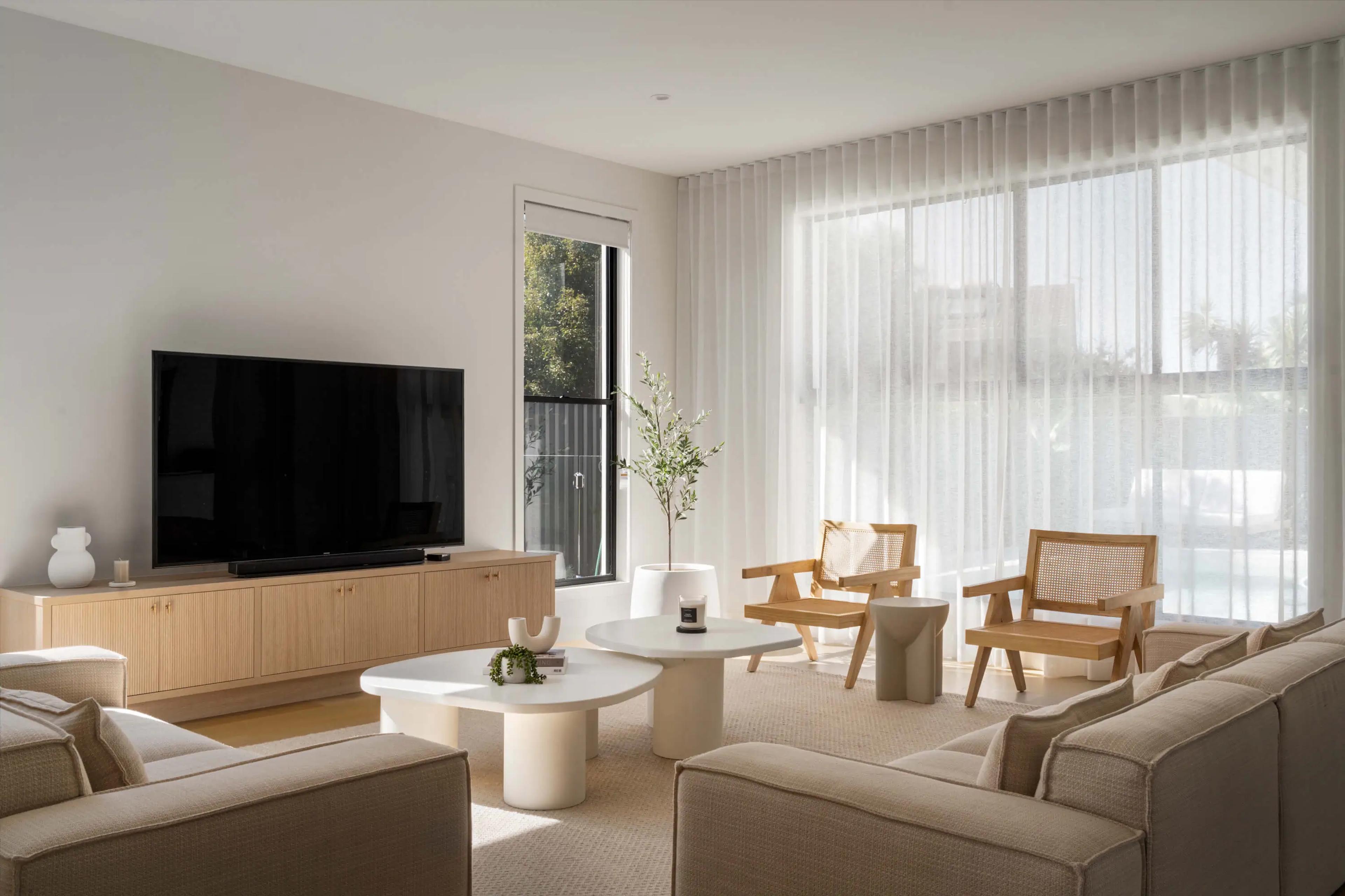 Living room with neutral sofas, timber chairs and television