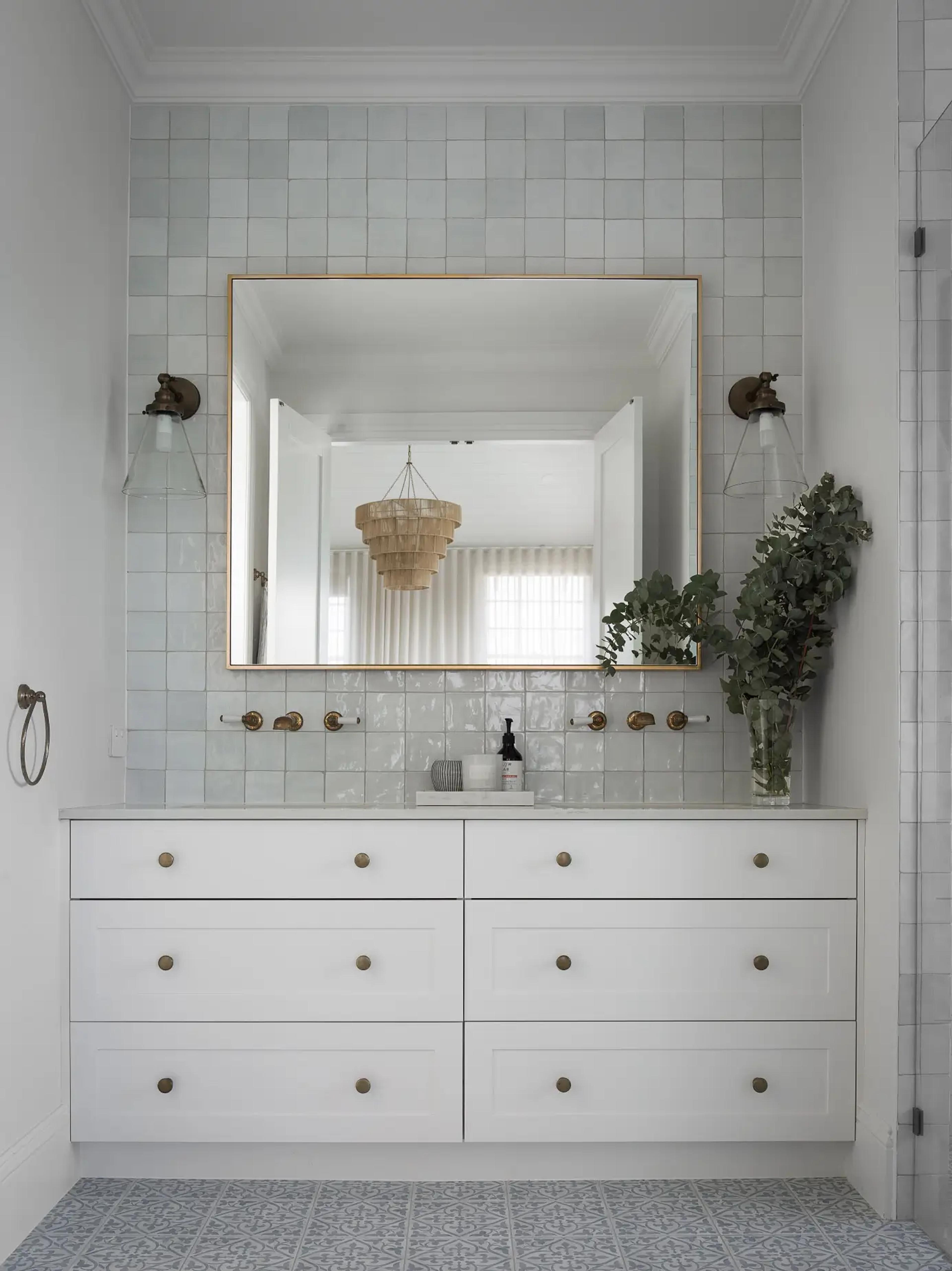 Bathroom vanity with gold framed mirror and blue wall tiles
