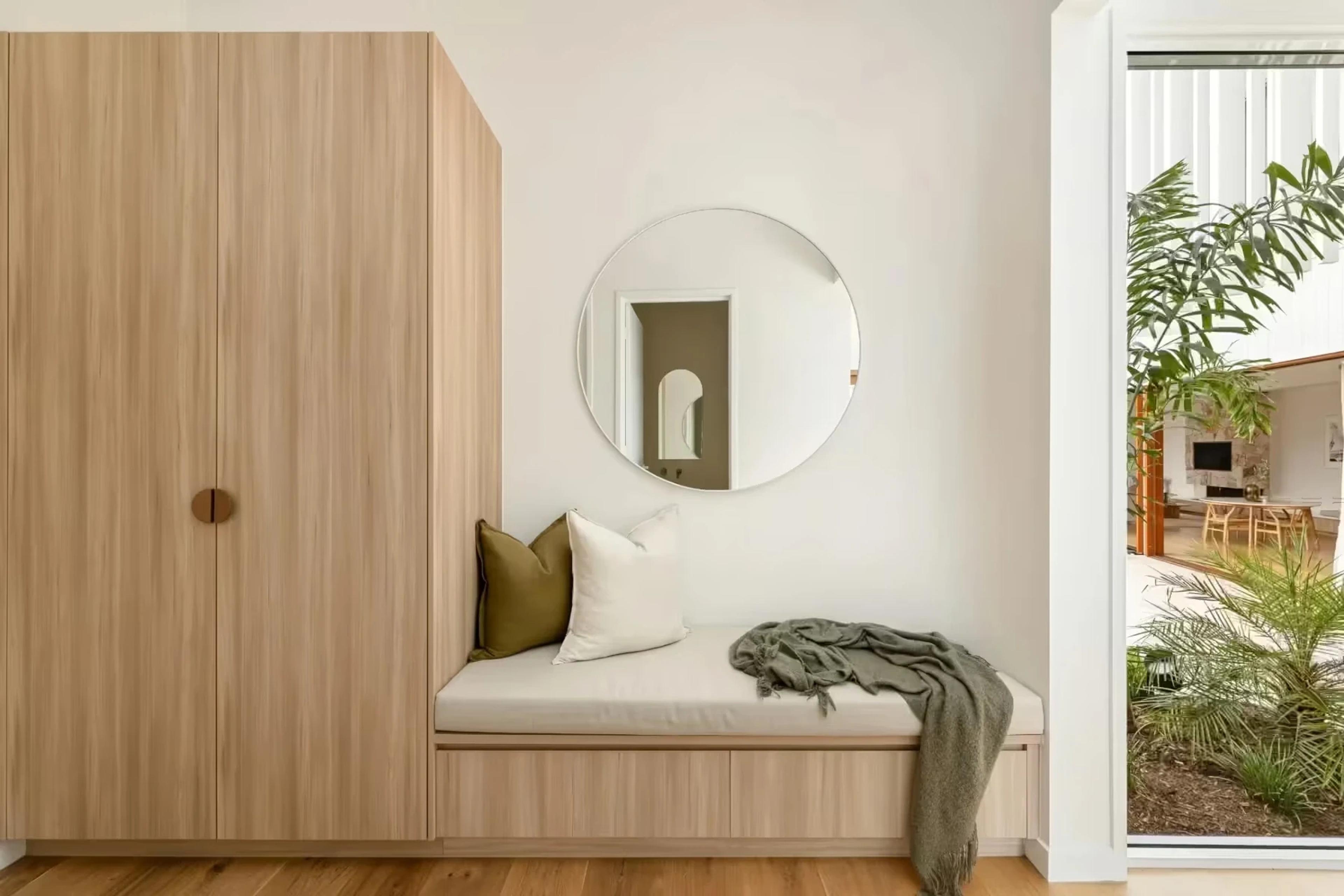 Entry nook with timber joinery, round mirror and bench seat