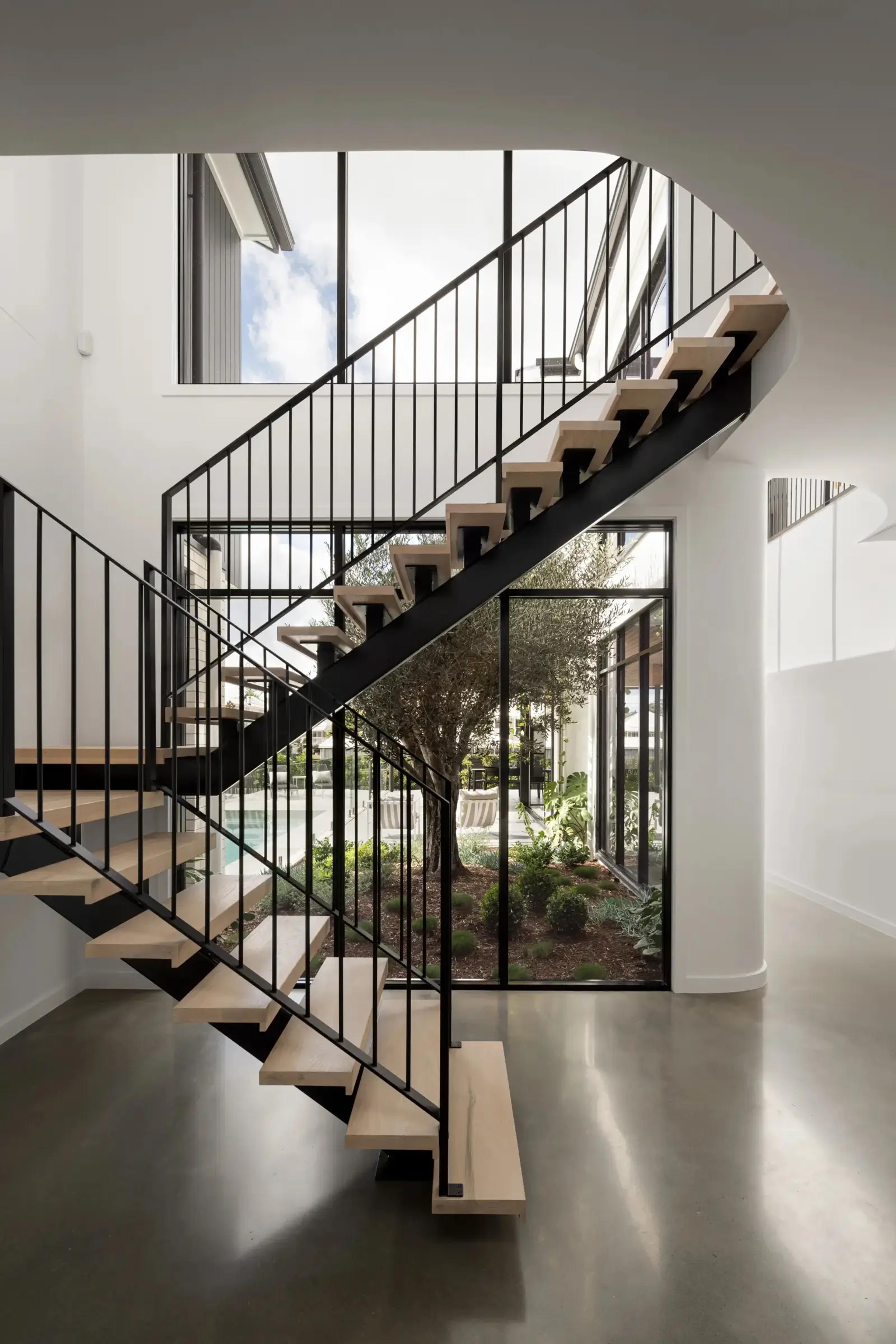 Steel and timber floating staircase beside tall courtyard window