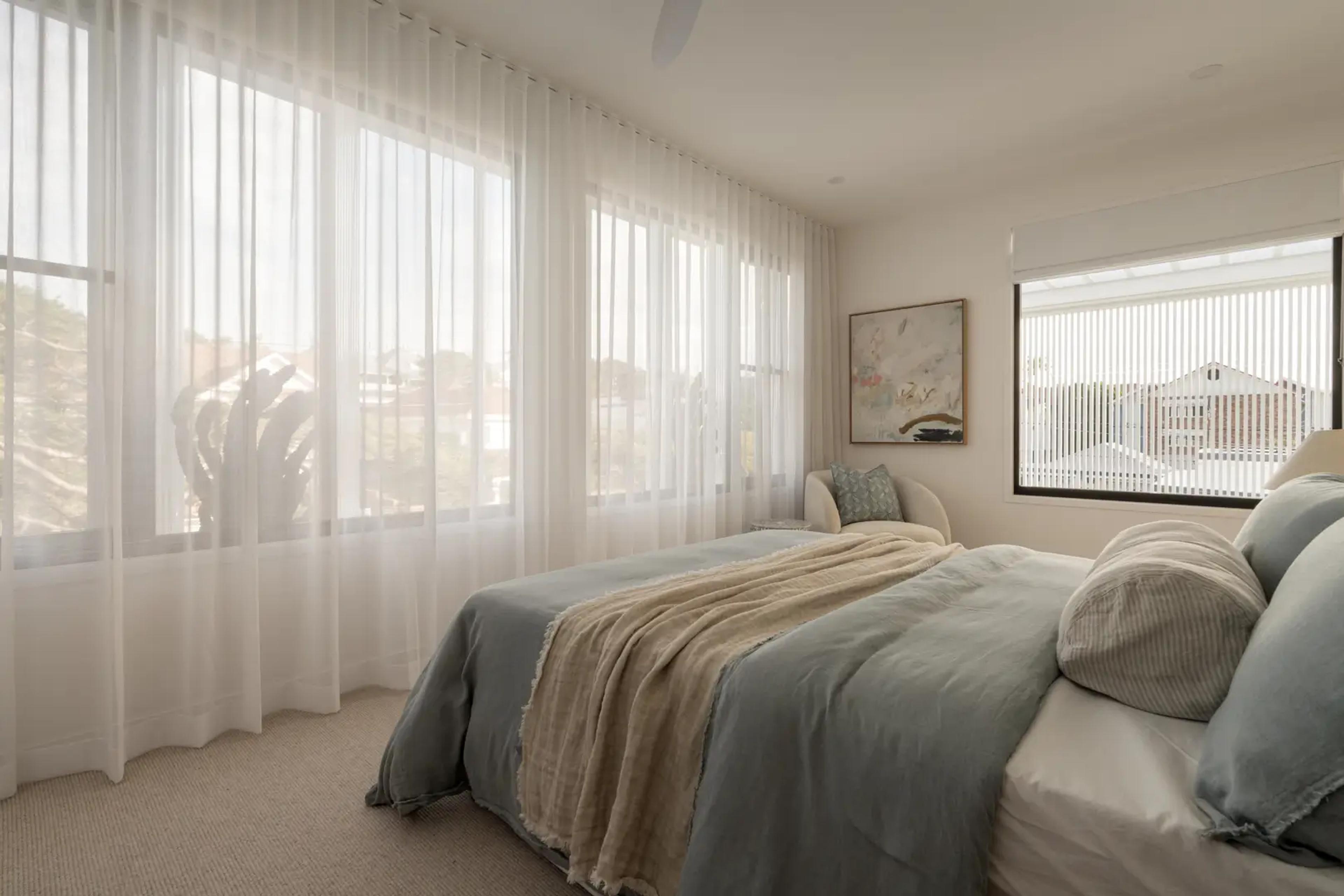 Bedroom with sheer curtains and grey linen bedding