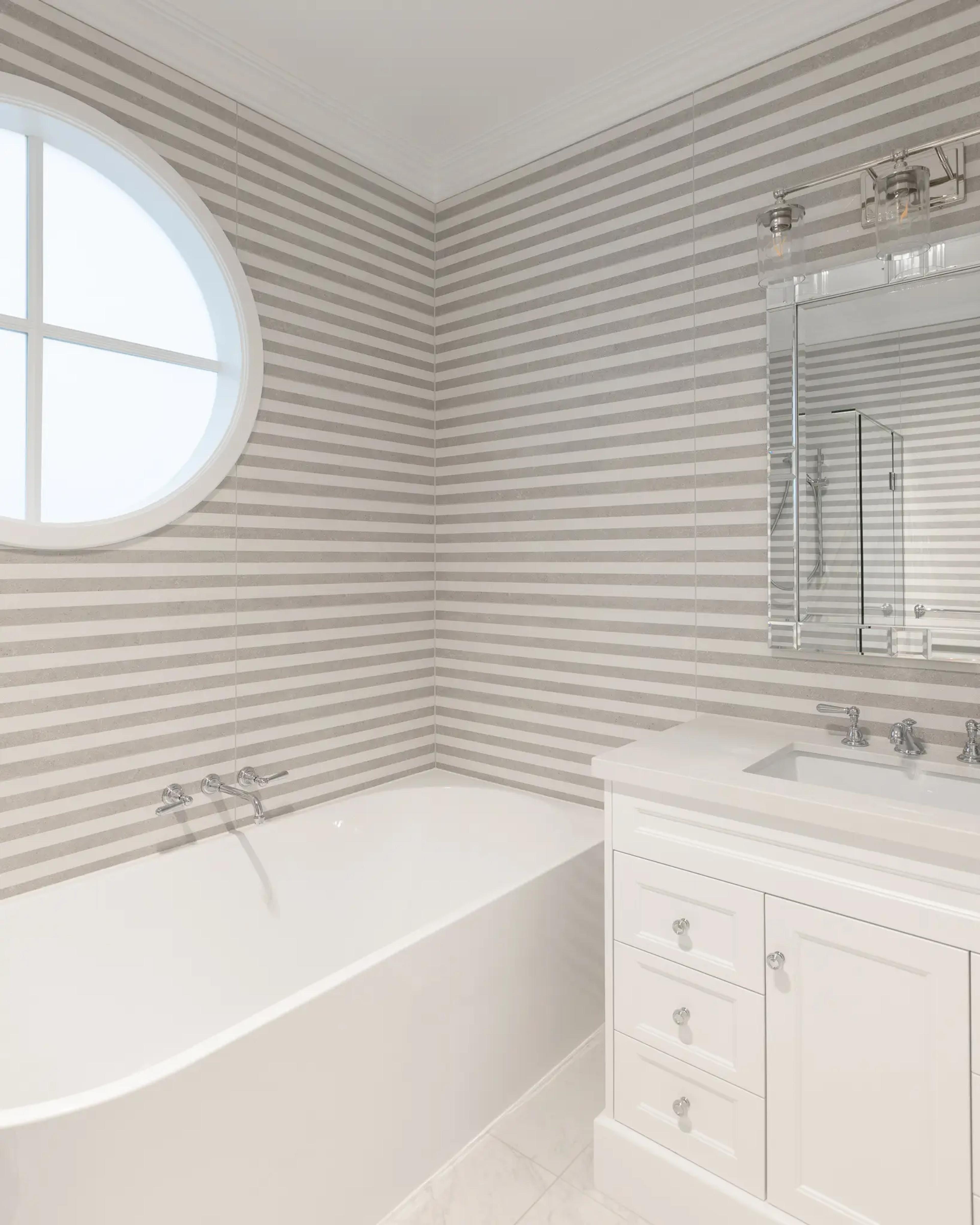 Bathroom with grey striped walls, freestanding bath and porthole window